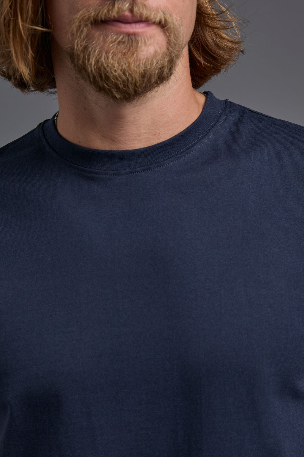 A blonde, male model with a beard wearing the men's core renewal tee in the color navy and black Levi 501® jeans from a front close up view on a gray background. The core renewal tee is made out of a sustainable blend of repurposed recycled garments: 60% recycled cotton and 40% recycled polyester. #navy