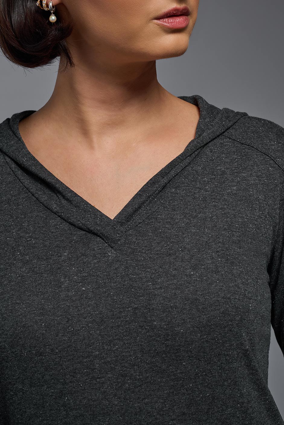 A female model wearing the women's Heather Hoodie Shirt in the color dark heather charcoal, made out of 88% polyester and 22% treated cotton, showing the relaxed fit from a front collar closeup view. This hoodie shirt is comfortable and made in the USA. #dark-heather-charcoal