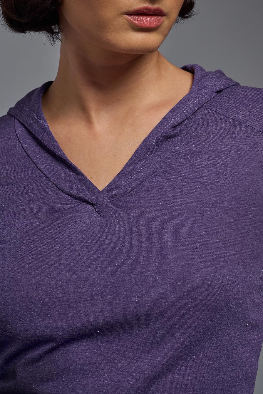 A female model wearing the women's Heather Hoodie Shirt in the color dark purple heather, made out of 88% polyester and 22% treated cotton, showing the relaxed fit from a closeup collar front view. This hoodie shirt is comfortable and made in the USA. #dark-heather-purple