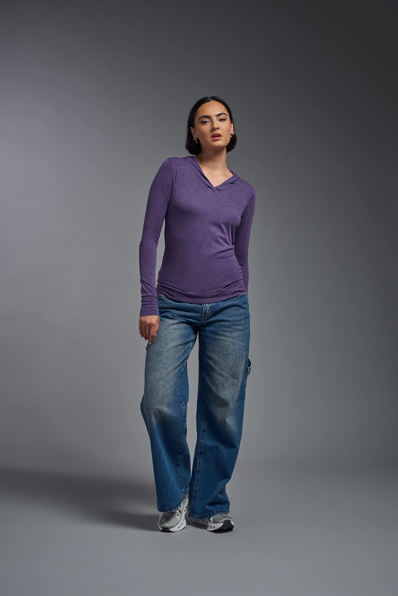 A female model wearing the women's Heather Hoodie Shirt in the color dark purple heather, made out of 88% polyester and 22% treated cotton, showing the relaxed fit from a front view. This hoodie shirt is comfortable and made in the USA. #dark-heather-purple