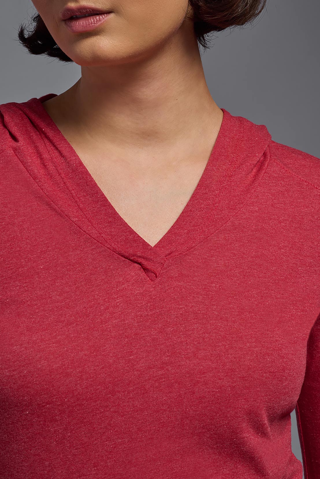 A female model wearing the women's Heather Hoodie Shirt in the color dark heather red, made out of 88% polyester and 22% treated cotton, showing the relaxed fit from a front closeup collar view. This hoodie shirt is comfortable and made in the USA. #dark-heather-red