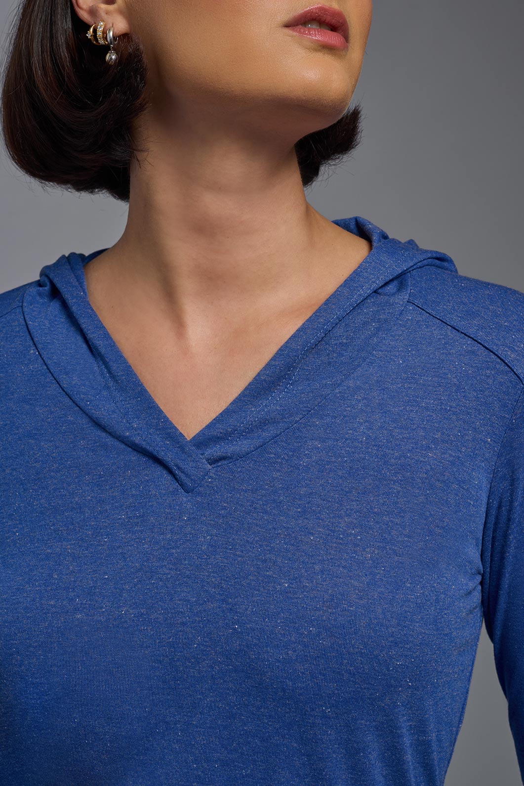A female model wearing the women's Heather Hoodie Shirt in the color dark heather royal blue, made out of 88% polyester and 22% treated cotton, showing the relaxed fit from a front collar closeup view. This hoodie shirt is comfortable and made in the USA. #dark-heather-royal