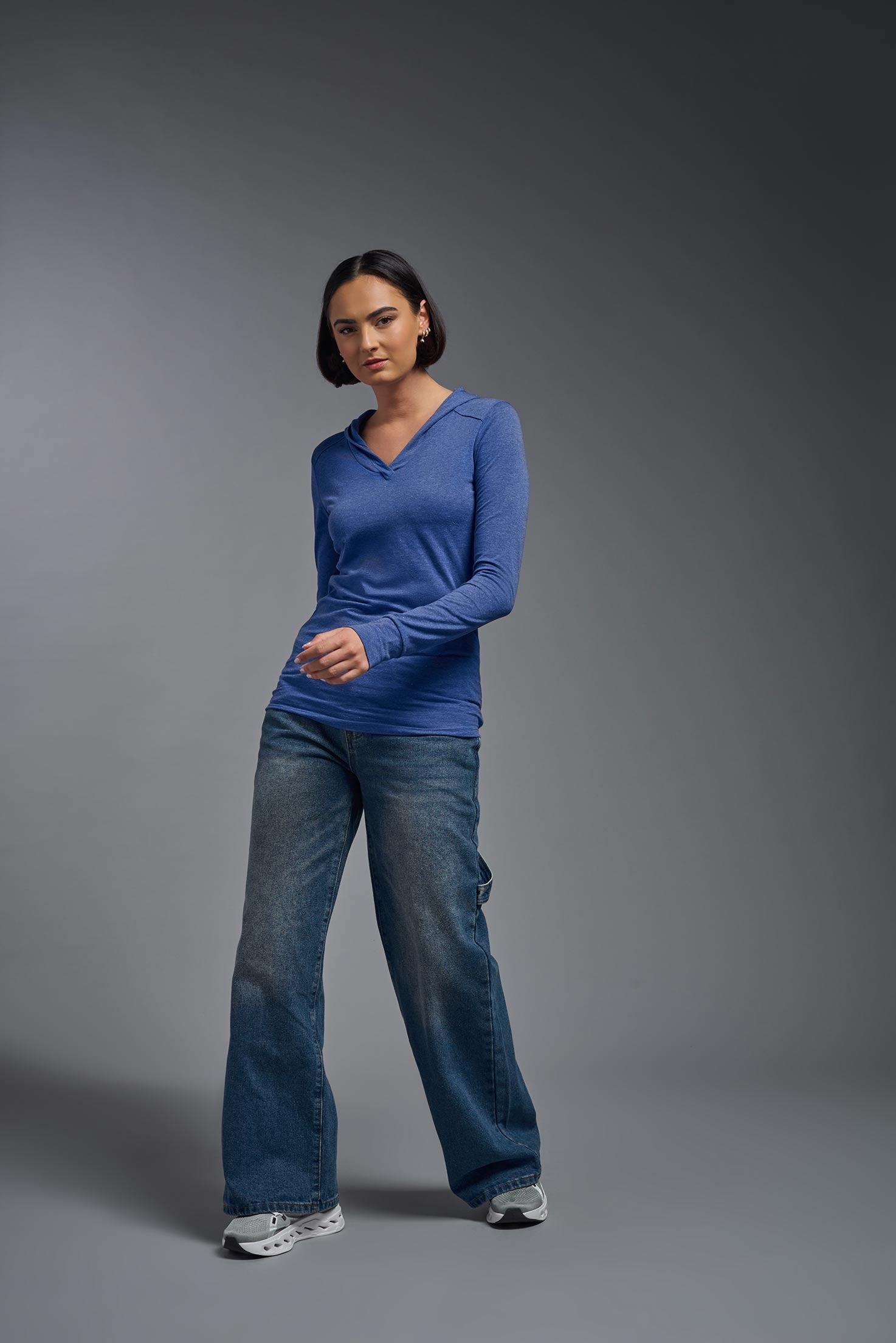 A female model wearing the women's Heather Hoodie Shirt in the color dark heather royal blue, made out of 88% polyester and 22% treated cotton, showing the relaxed fit from a front view. This hoodie shirt is comfortable and made in the USA. #dark-heather-royal
