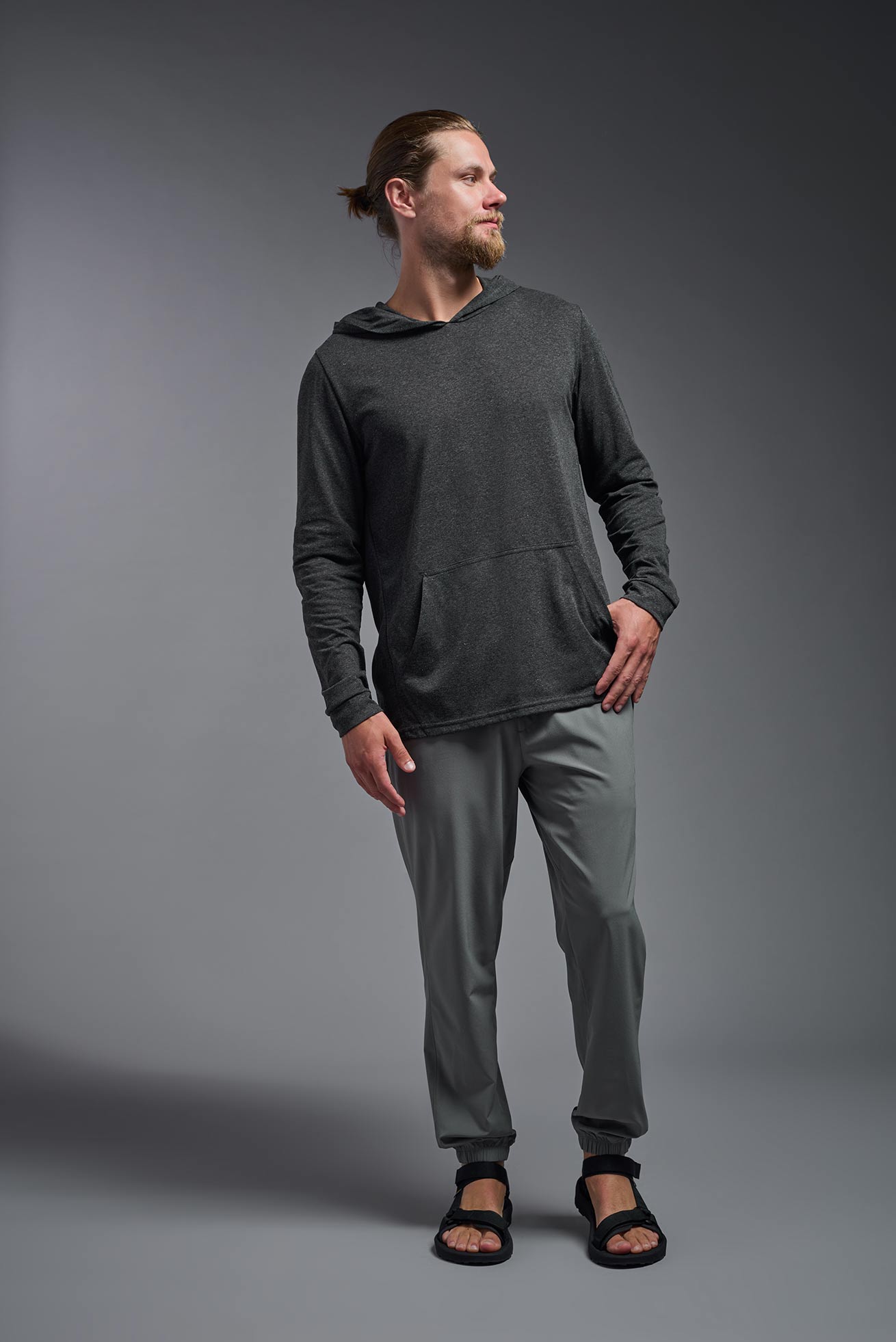 A male model wearing the men's Heather Hoodie Shirt in the color dark heather charcoal, made out of 88% polyester and 22% treated cotton, showing the relaxed fit from a closeup front view. This hoodie shirt is comfortable and made in the USA. #color_dark-heather-charcoal