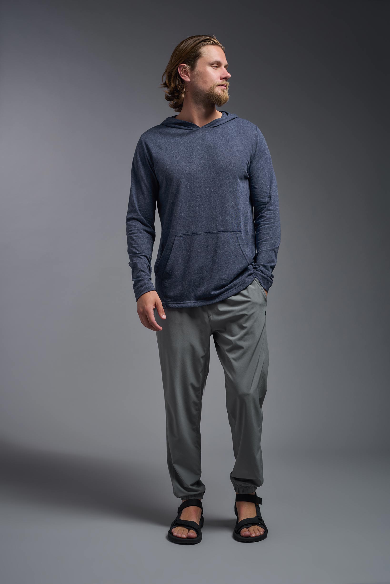 A male model wearing the men's Heather Hoodie Shirt in the color dark heather navy, made out of 88% polyester and 22% treated cotton, showing the relaxed fit from a closeup front view. This hoodie shirt is comfortable and made in the USA. #color_dark-heather-navy