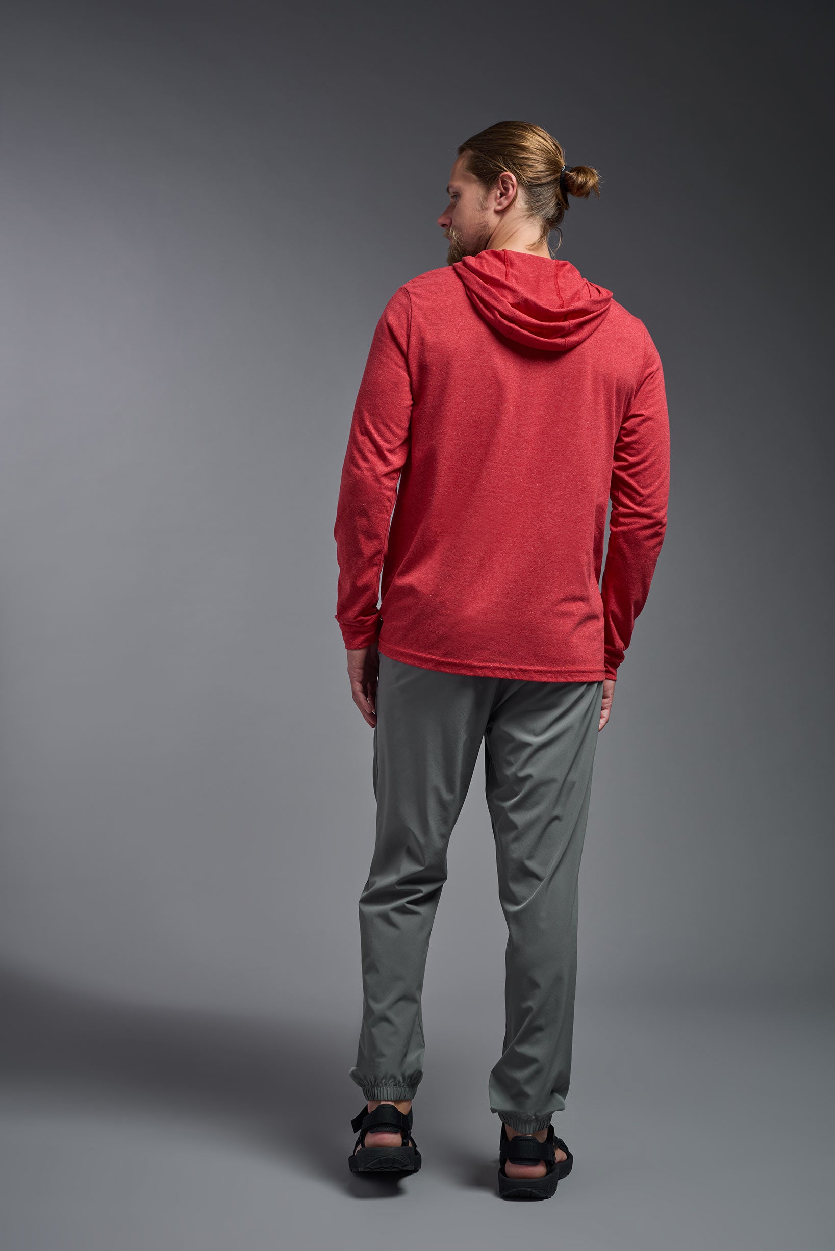 A male model wearing the men's Heather Hoodie Shirt in the color dark heather red, made out of 88% polyester and 22% treated cotton, showing the relaxed fit from a back view. This hoodie shirt is comfortable and made in the USA. #color_dark-heather-red