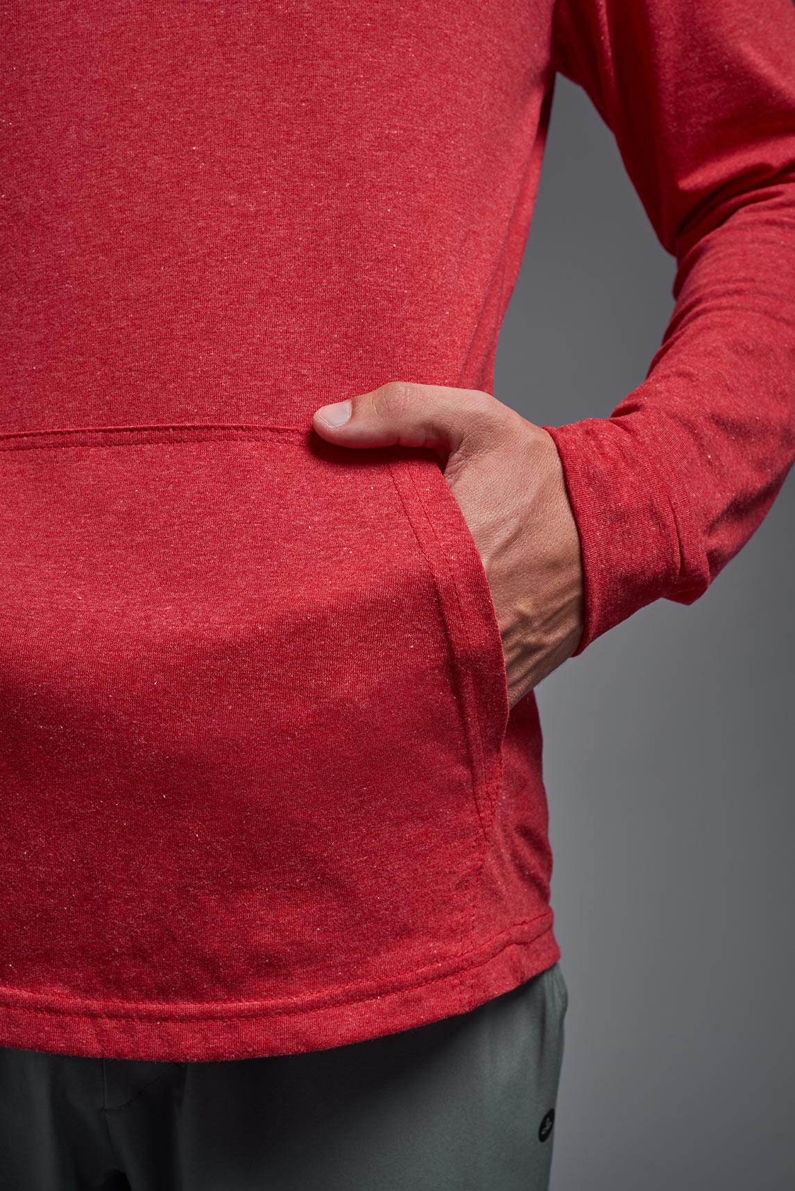 A male model wearing the men's Heather Hoodie Shirt in the color dark heather red, made out of 88% polyester and 22% treated cotton, showing the relaxed fit from a closeup front pocket view. This hoodie shirt is comfortable and made in the USA. #color_dark-heather-red