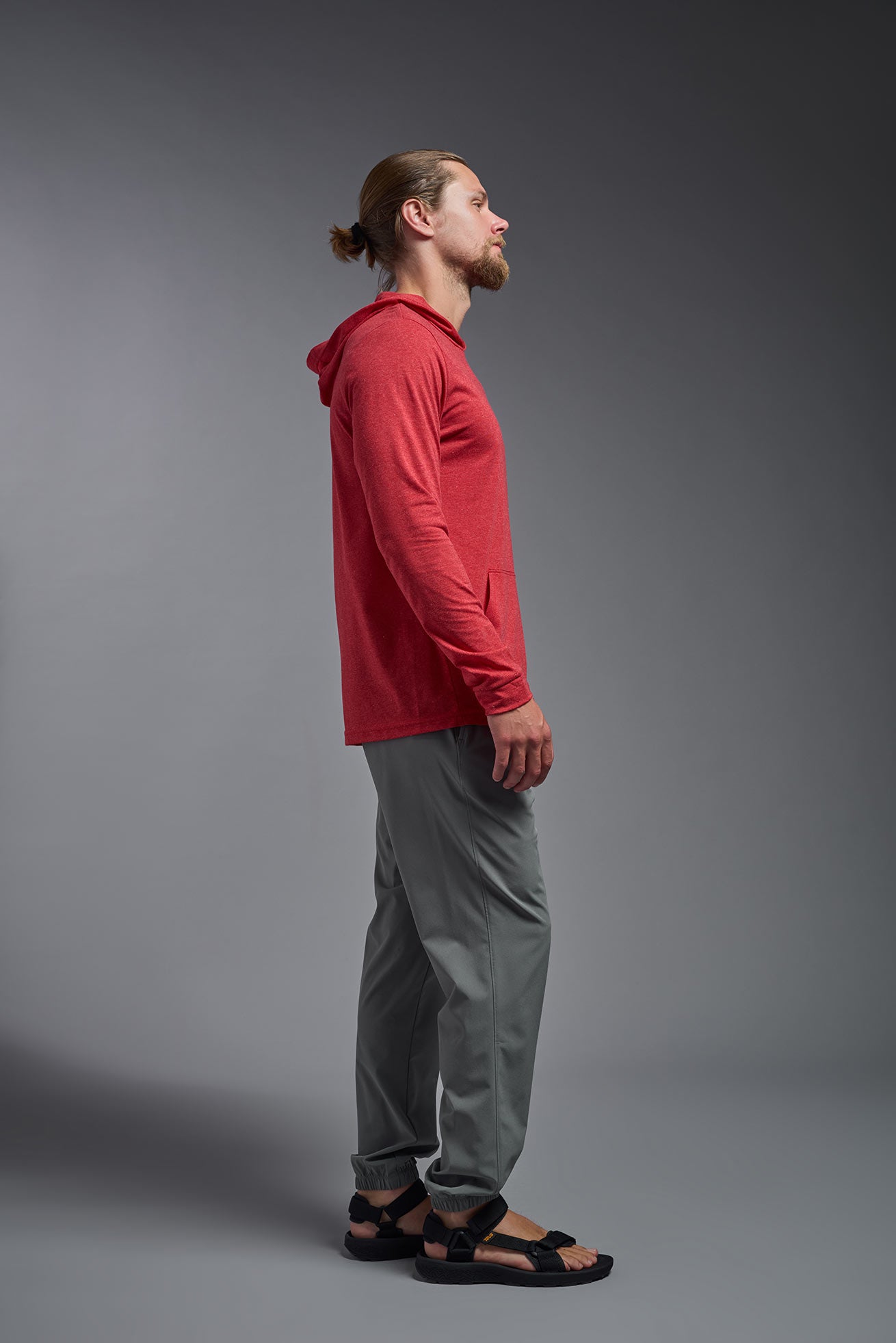 A male model wearing the men's Heather Hoodie Shirt in the color dark heather red, made out of 88% polyester and 22% treated cotton, showing the relaxed fit from a side view. This hoodie shirt is comfortable and made in the USA. #color_dark-heather-red