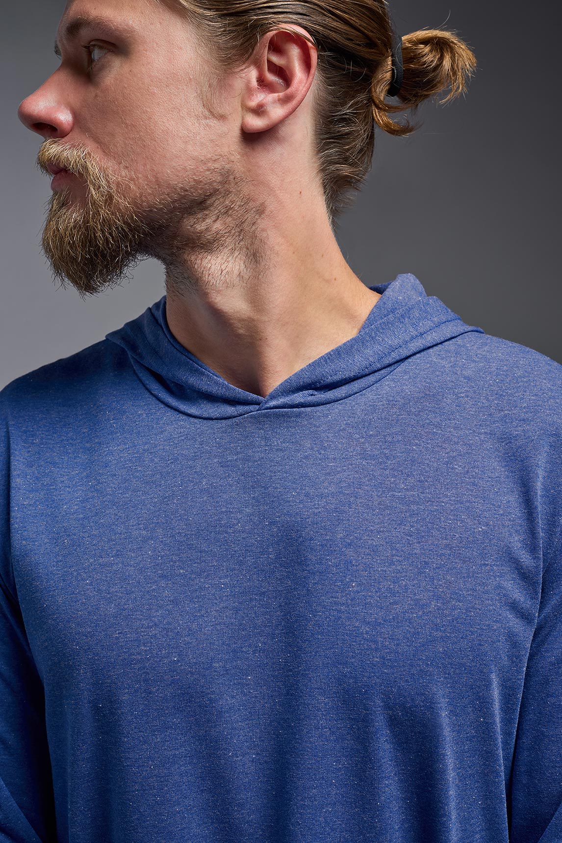A male model wearing the men's Heather Hoodie Shirt in the color dark heather royal, made out of 88% polyester and 22% treated cotton, showing the relaxed fit from a front closeup collar view. This hoodie shirt is comfortable and made in the USA. #color_dark-heather-royal