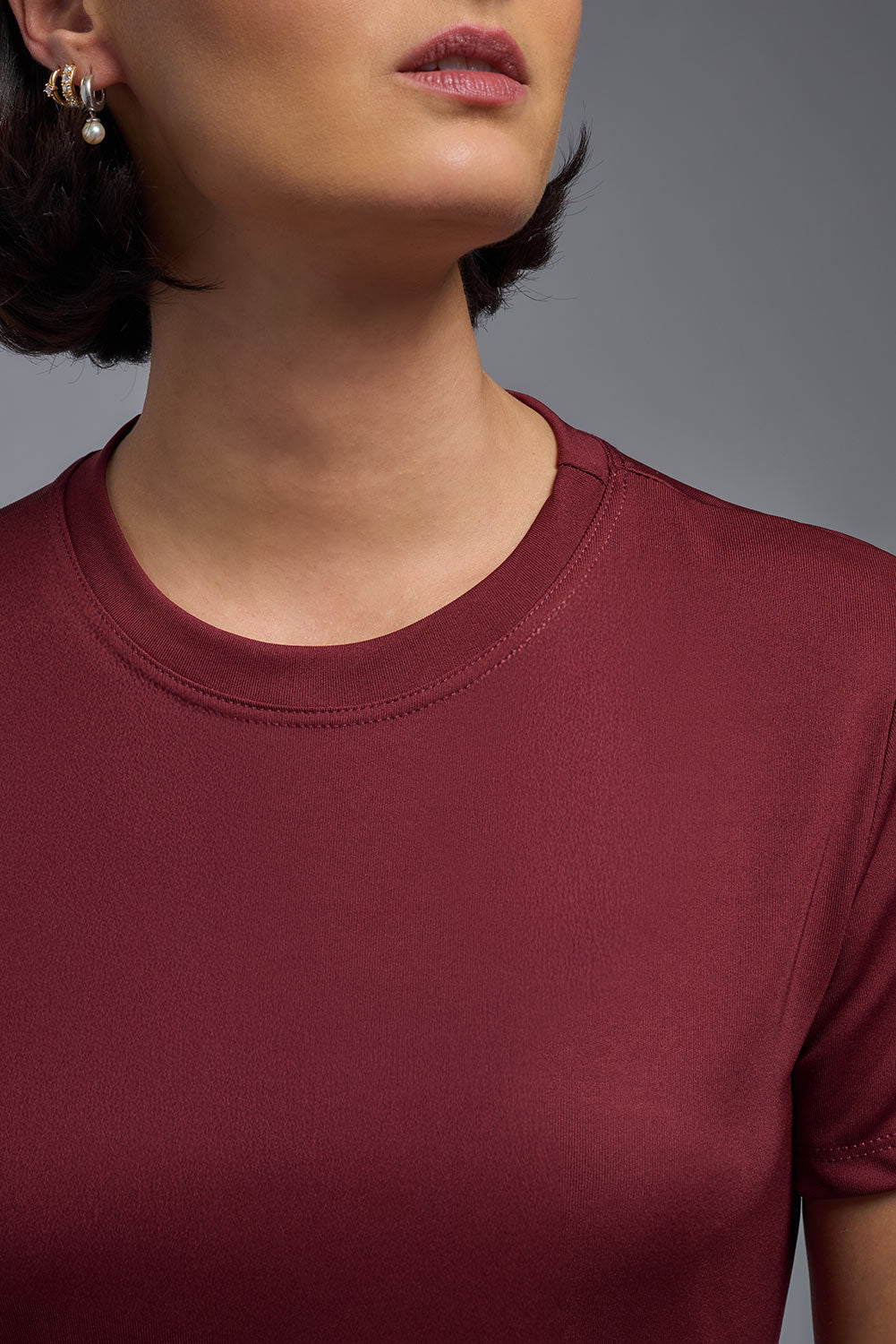 A female model wearing the women's DriMax Crewneck Expert Tee in cardinal, made out of 100% polyester, showing the relaxed fit from a collar view. This shirt is quick-drying, moisture-wicking, offers up to 30 upf protection and is made in the USA. #cardinal