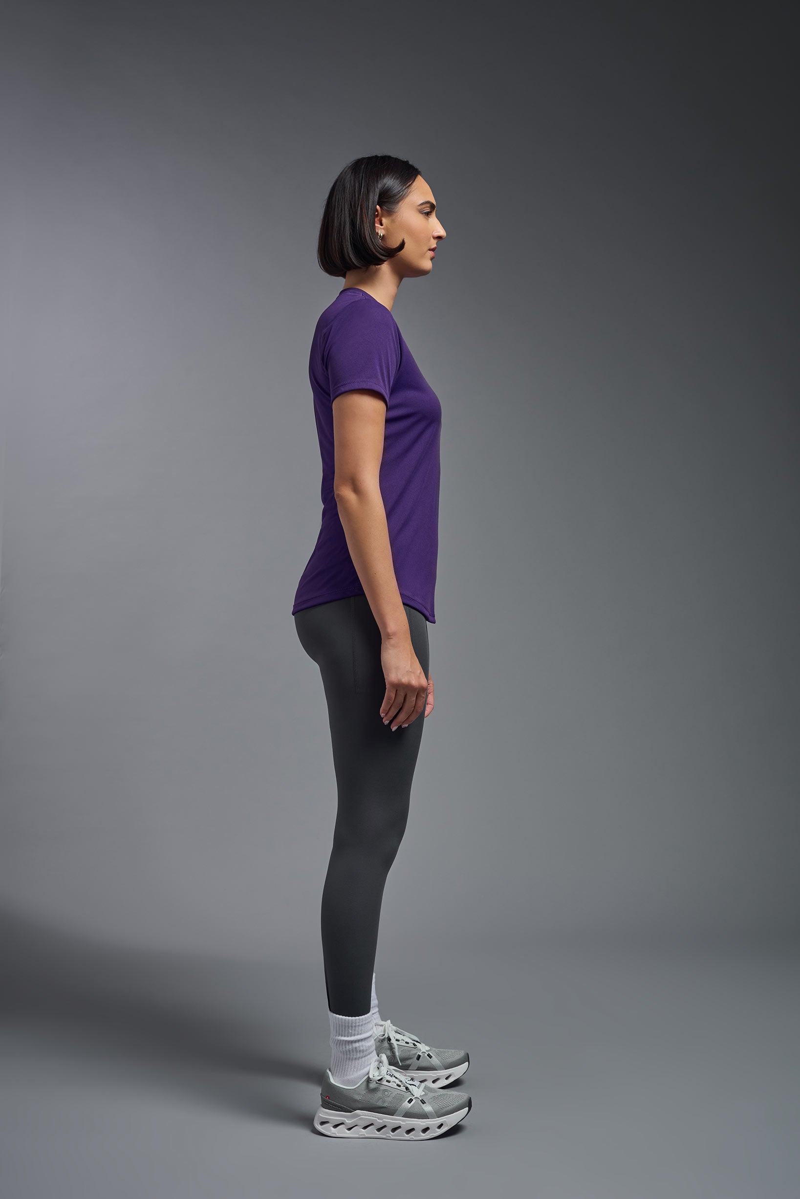 A female model wearing the women's DriMax Crewneck Expert Tee in the color dark purple, made out of 100% polyester, showing the relaxed fit from a side view. This shirt is quick-drying, moisture-wicking, offers up to 30 upf protection and is made in the USA. #deep-purple