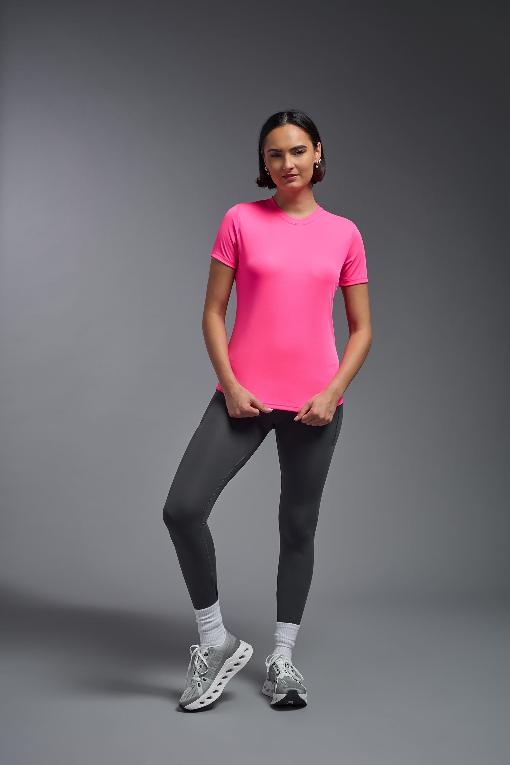 A female model wearing the women's DriMax Crewneck Expert Tee in the color hot pink, made out of 100% polyester, showing the relaxed fit from a front view. This shirt is quick-drying, moisture-wicking, offers up to 30 upf protection and is made in the USA. #hot-pink