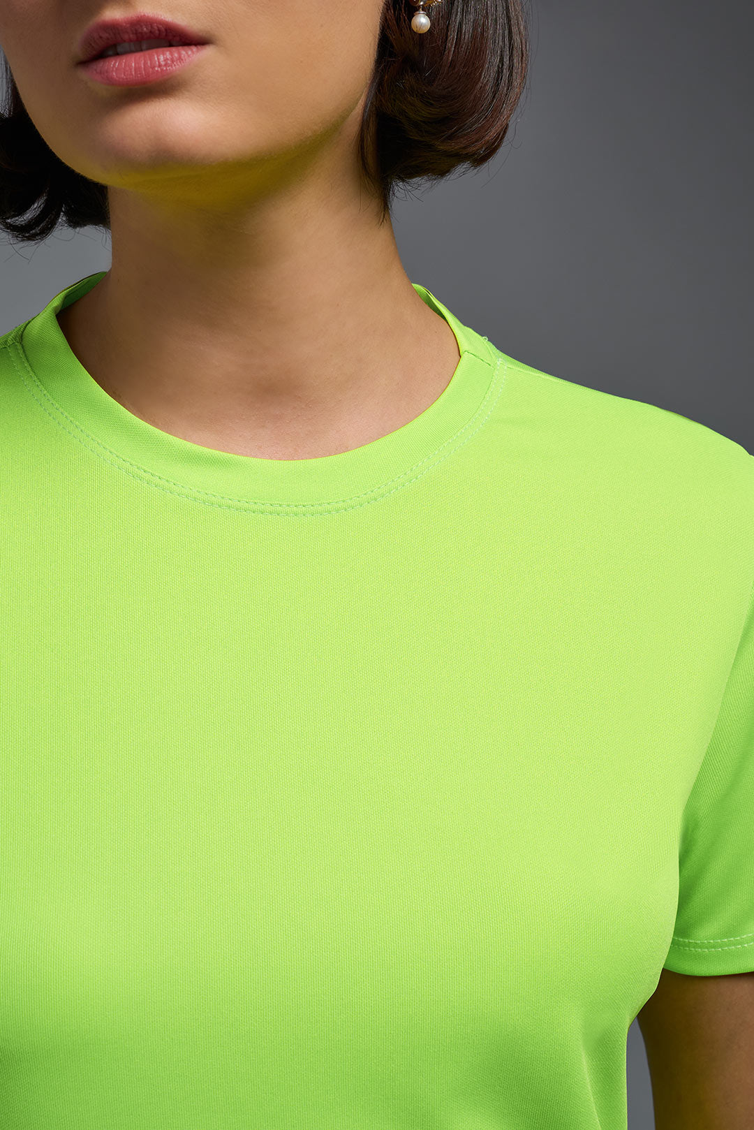 A female model wearing the women's DriMax Crewneck Expert Tee in the color safety yellow made out of 100% polyester, showing the relaxed fit from a closeup collar front view. This shirt is quick-drying, moisture-wicking, offers up to 30 upf protection and is made in the USA. #safety-yellow