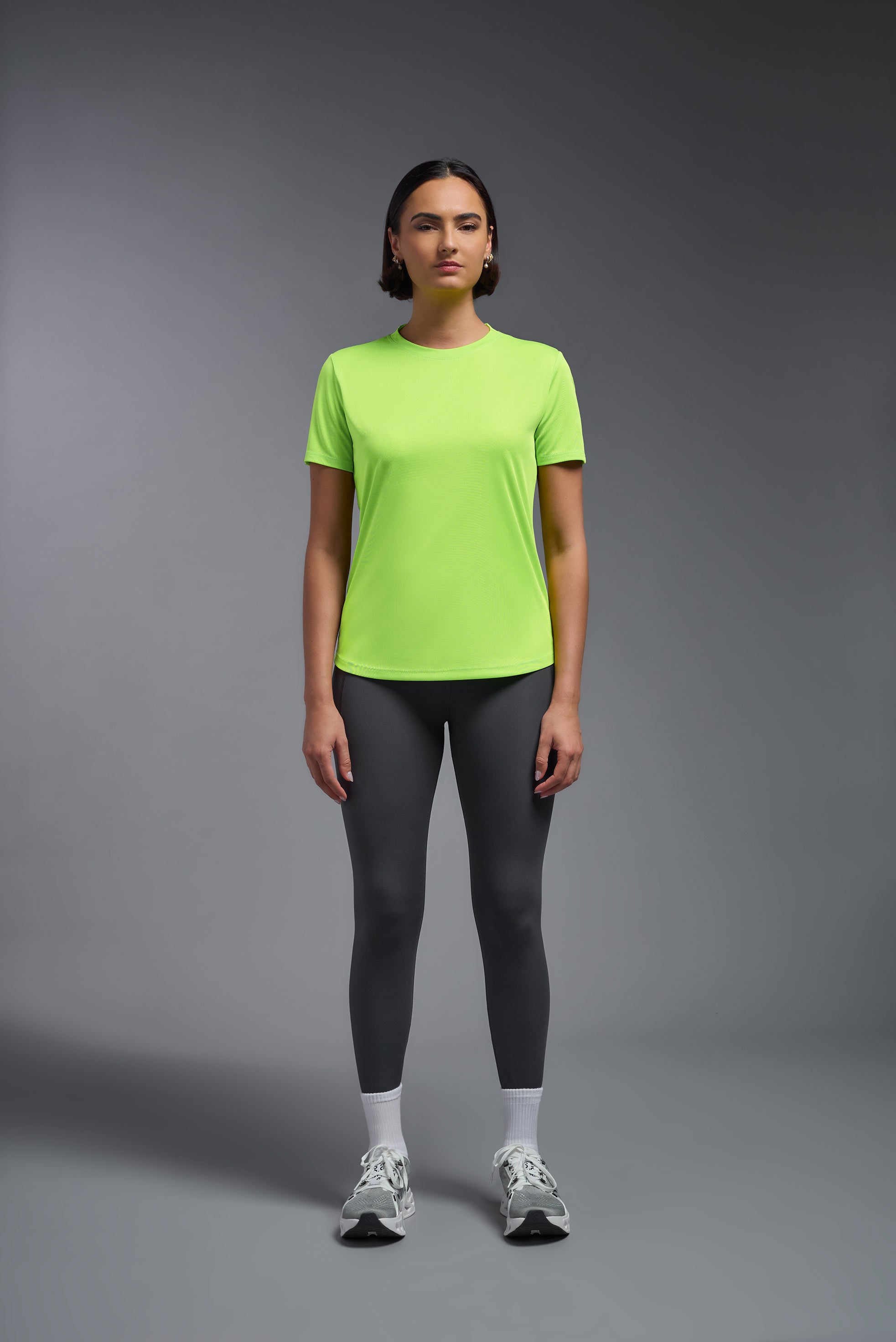 A female model wearing the women's DriMax Crewneck Expert Tee in the color safety yellow made out of 100% polyester, showing the relaxed fit from a front view. This shirt is quick-drying, moisture-wicking, offers up to 30 upf protection and is made in the USA. #safety-yellow