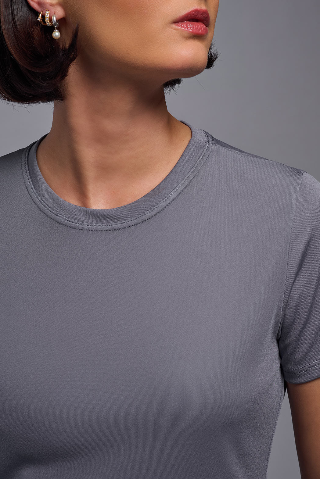 A female model wearing the women's DriMax Crewneck Expert Tee in the color steel gray made out of 100% polyester, showing the relaxed fit from a collar close-up view. This shirt is quick-drying, moisture-wicking, offers up to 30 upf protection and is made in the USA. #steel