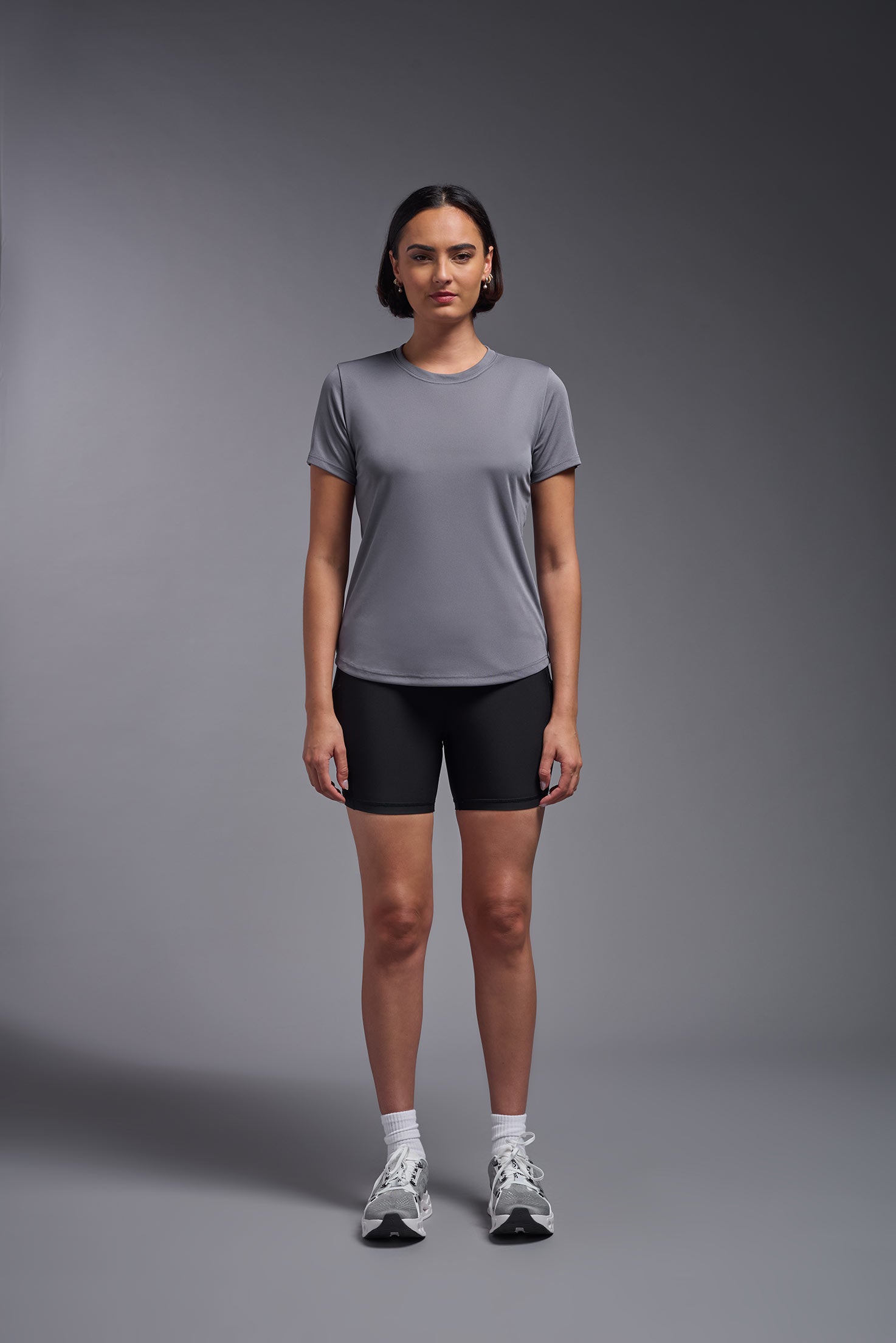 A female model wearing the women's DriMax Crewneck Expert Tee in the color steel gray made out of 100% polyester, showing the relaxed fit from a steel view. This shirt is quick-drying, moisture-wicking, offers up to 30 upf protection and is made in the USA. #steel