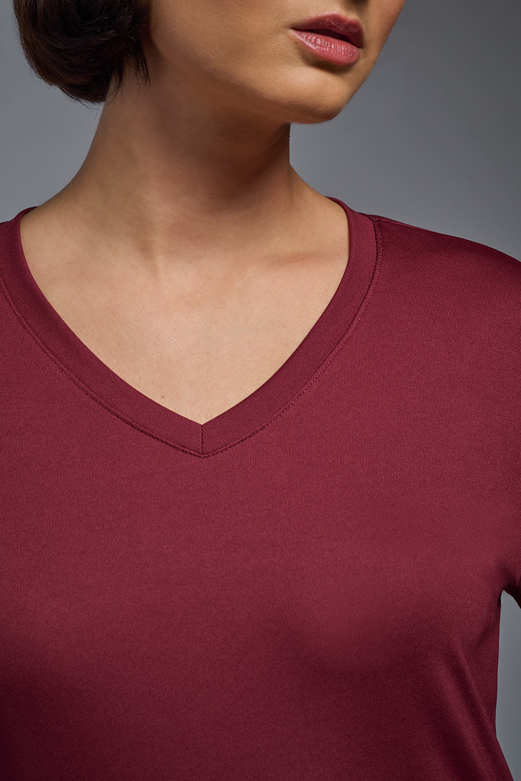 A female model wearing the women's DriMax V-Neck Long Sleeve Expert Tee  in the color cardinal, made out of 100% polyester, showing the relaxed fit from a close-up collar view. This shirt is quick-drying, moisture-wicking, with up to 30 UV protection and made in the USA. #cardinal