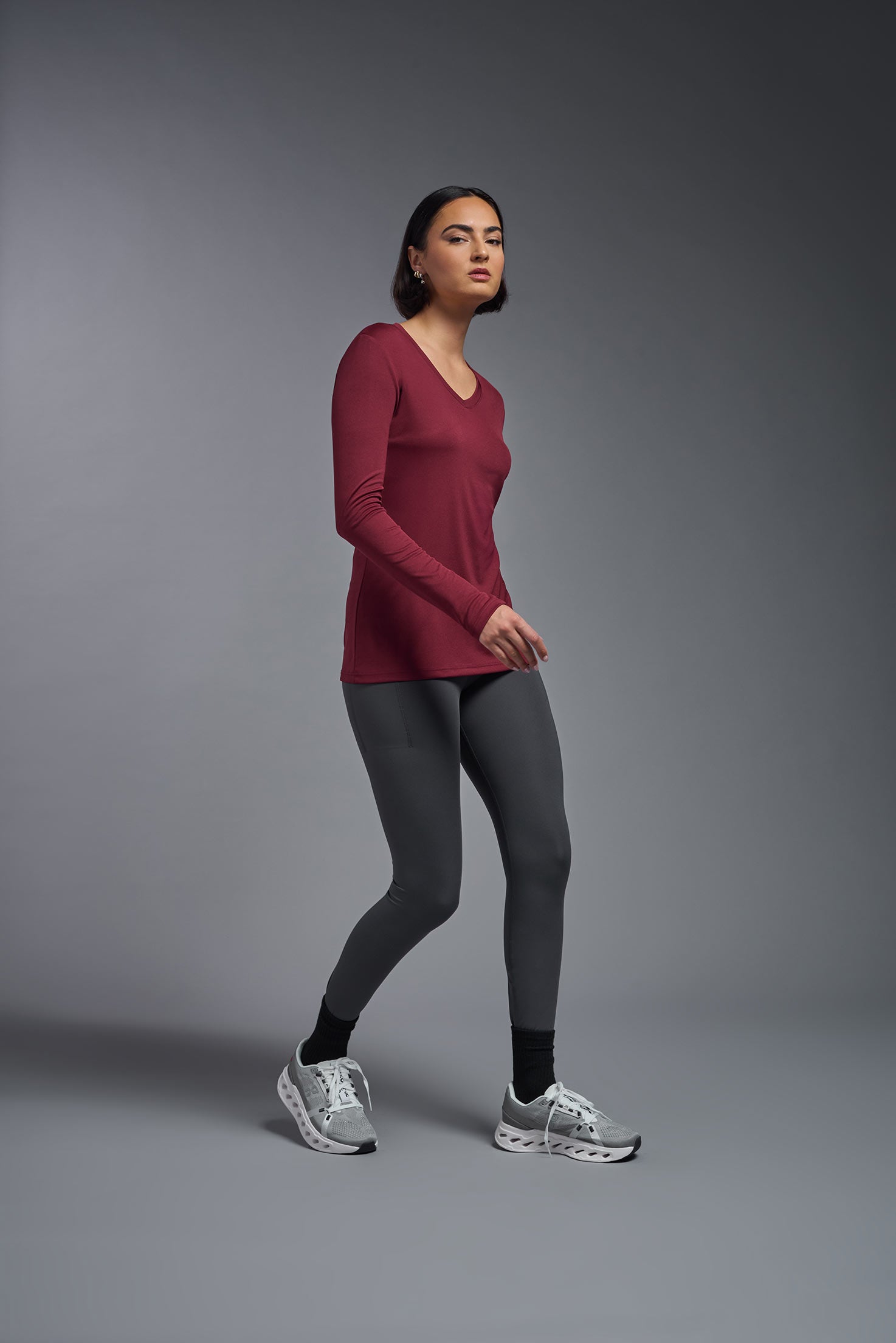 A female model wearing the women's DriMax V-Neck Long Sleeve Expert Tee  in the color cardinal, made out of 100% polyester, showing the relaxed fit from a side view. This shirt is quick-drying, moisture-wicking, with up to 30 UV protection and made in the USA. #cardinal
