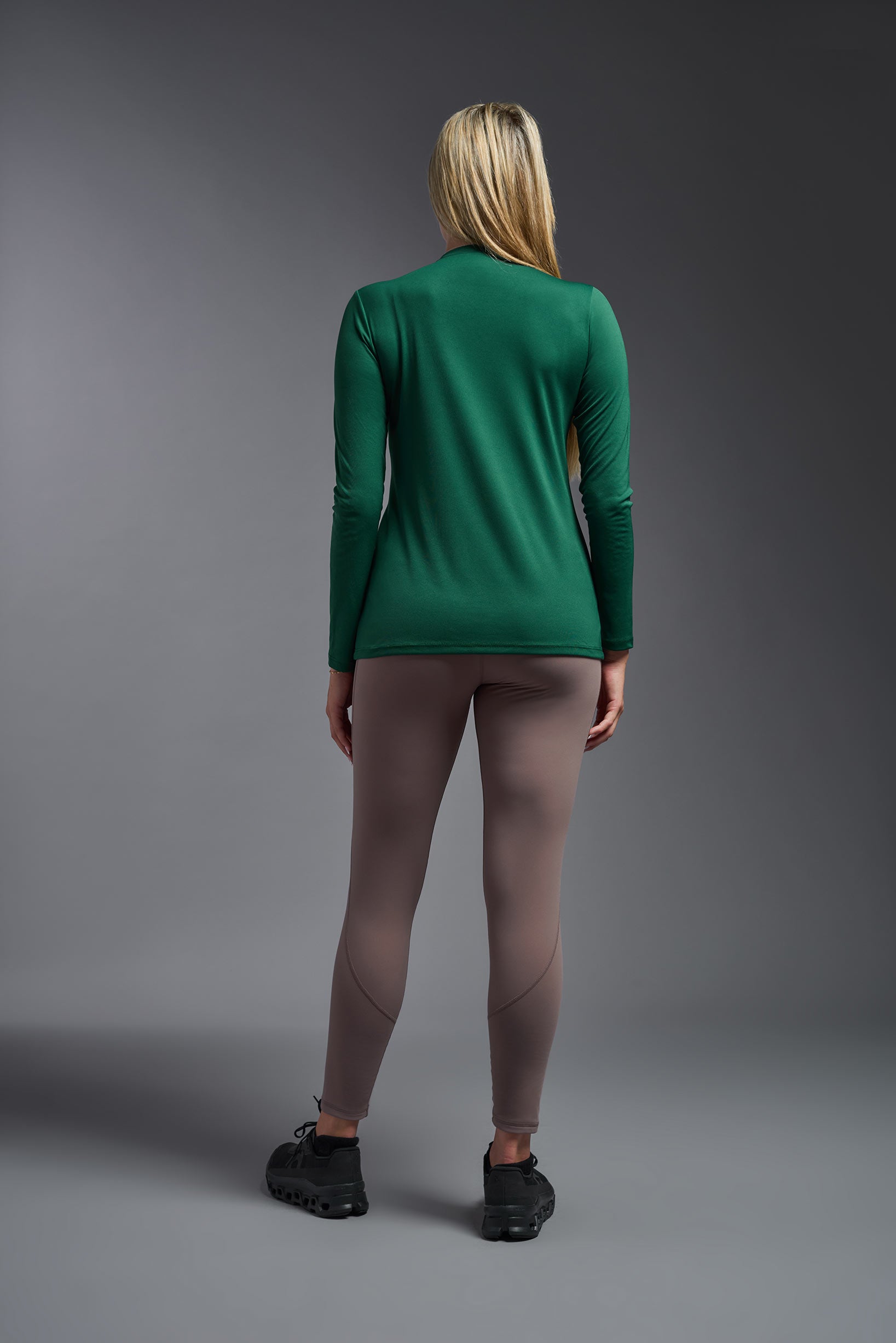 A female model wearing the women's DriMax V-Neck Long Sleeve Expert Tee  in the color forest-green, made out of 100% polyester, showing the relaxed fit from a back view. This shirt is quick-drying, moisture-wicking, with up to 30 UV protection and made in the USA. #forest