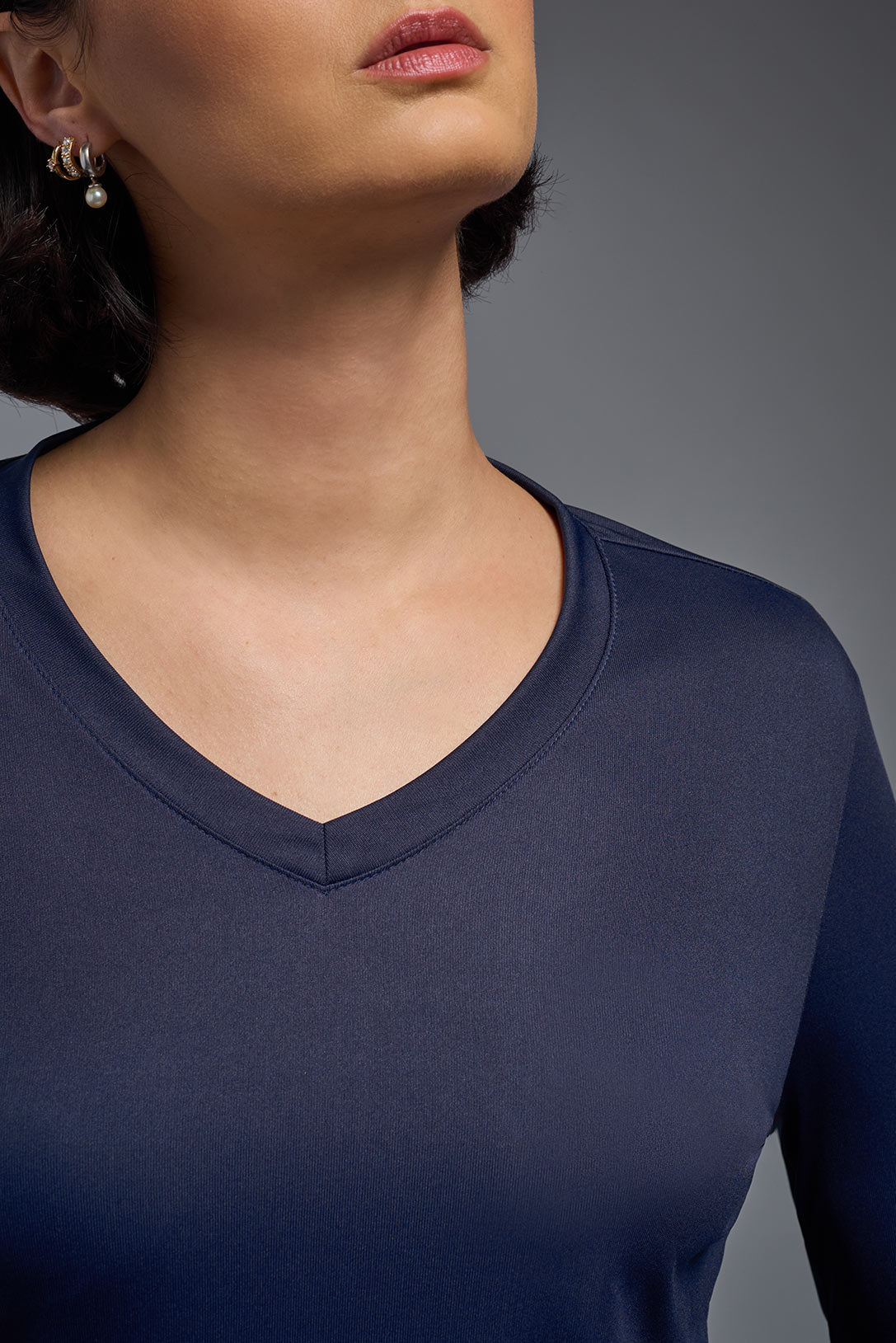 A female model wearing the women's DriMax V-Neck Long Sleeve Expert Tee  in the color navy, made out of 100% polyester, showing the relaxed fit from a close-up collar view. This shirt is quick-drying, moisture-wicking, with up to 30 UV protection and made in the USA. #navy