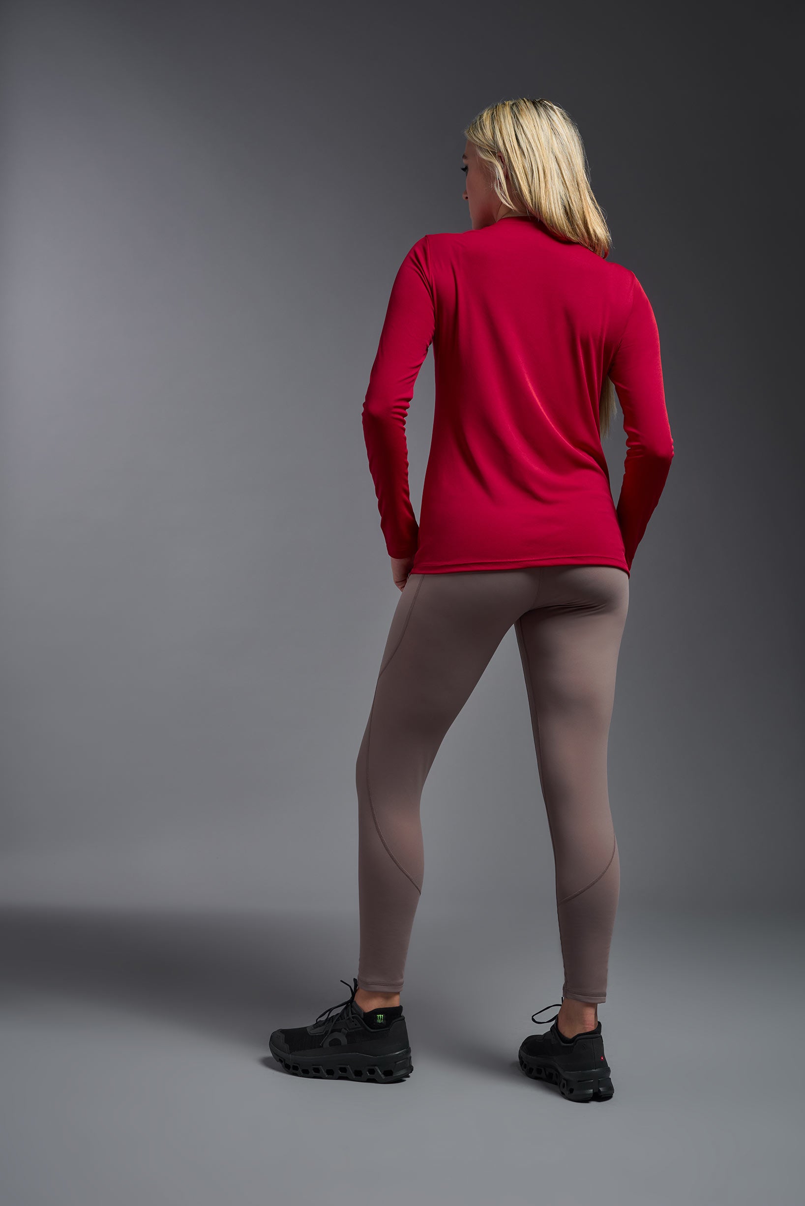 A female model wearing the women's DriMax V-Neck Long Sleeve Expert Tee  in the color red, made out of 100% polyester, showing the relaxed fit from a back view. This shirt is quick-drying, moisture-wicking, with up to 30 UV protection and made in the USA. #red
