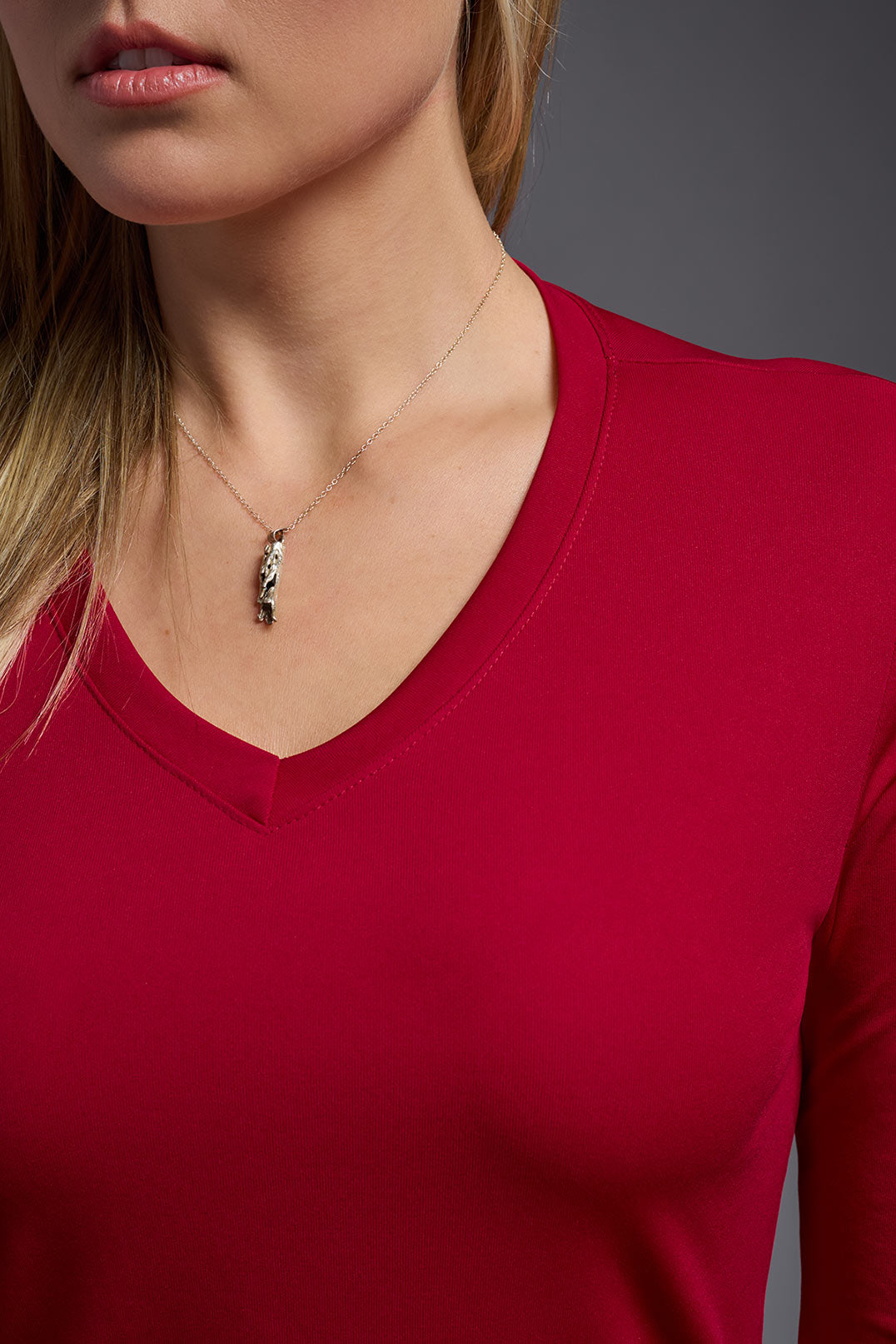 A female model wearing the women's DriMax V-Neck Long Sleeve Expert Tee  in the color red, made out of 100% polyester, showing the relaxed fit from a close-up collar view. This shirt is quick-drying, moisture-wicking, with up to 30 UV protection and made in the USA. #red