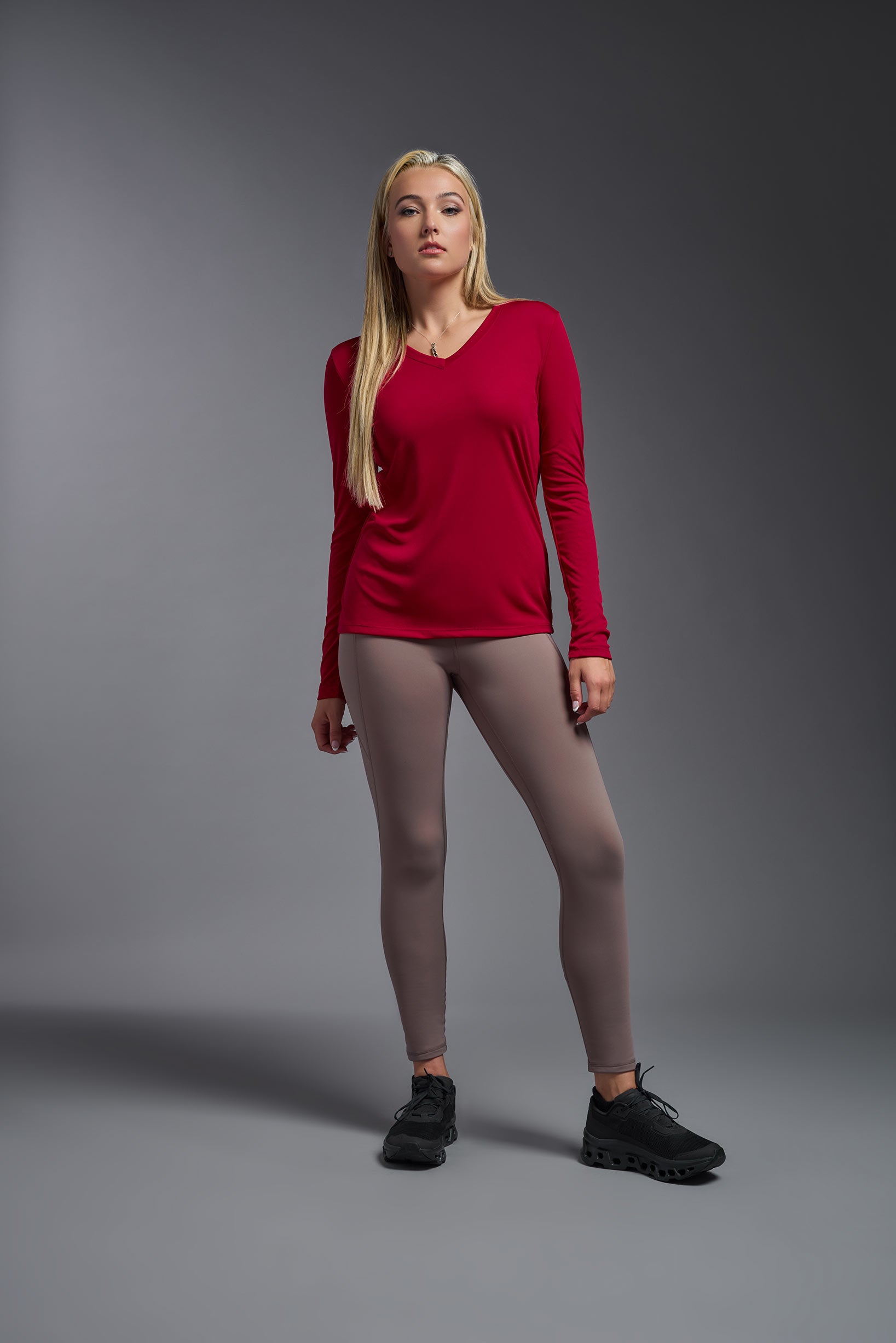 A female model wearing the women's DriMax V-Neck Long Sleeve Expert Tee  in the color red, made out of 100% polyester, showing the relaxed fit from a front view. This shirt is quick-drying, moisture-wicking, with up to 30 UV protection and made in the USA. #red