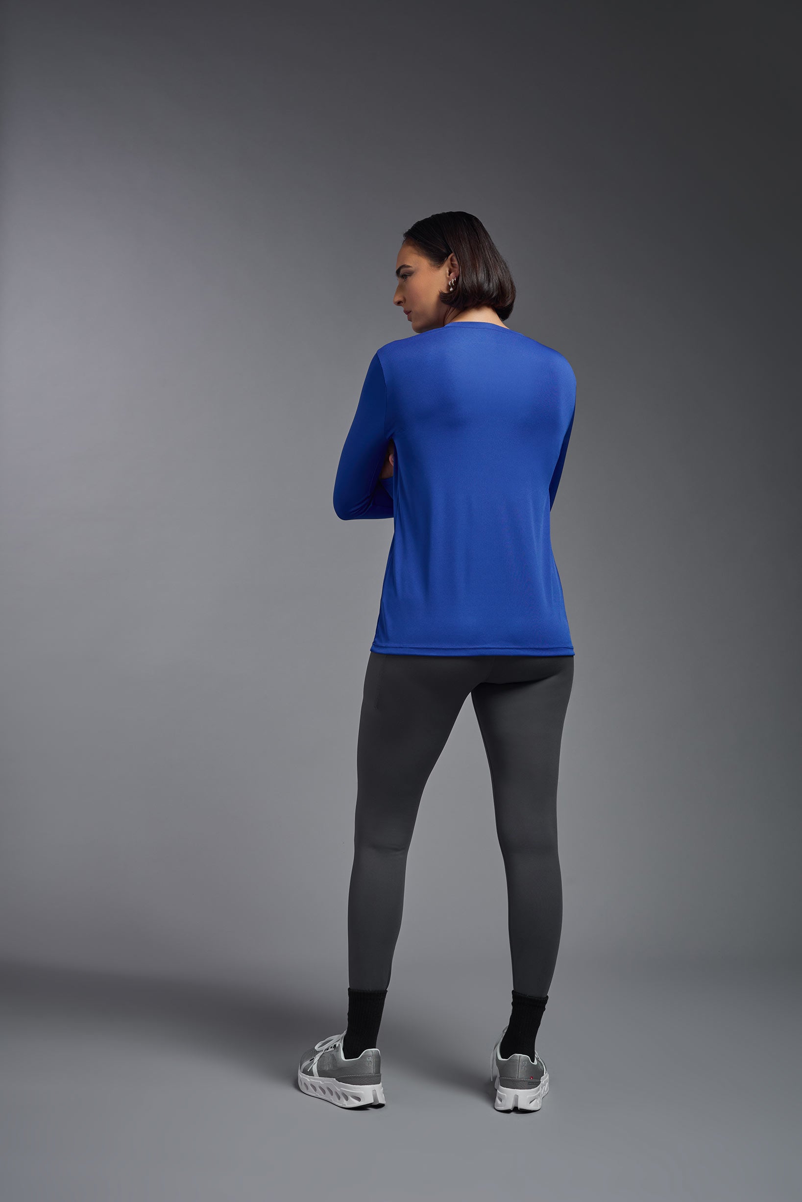 A female model wearing the women's DriMax V-Neck Long Sleeve Expert Tee  in the color royal blue, made out of 100% polyester, showing the relaxed fit from a back view. This shirt is quick-drying, moisture-wicking, with up to 30 UV protection and made in the USA. #royal