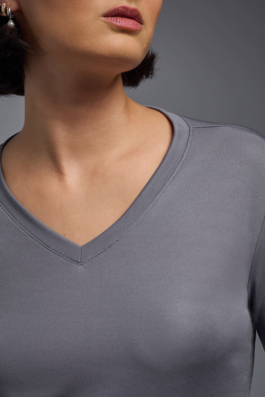 A female model wearing the women's DriMax V-Neck Long Sleeve Expert Tee  in the color steel gray, made out of 100% polyester, showing the relaxed fit from a close-up collar view. This shirt is quick-drying, moisture-wicking, with up to 30 UV protection and made in the USA. #steel
