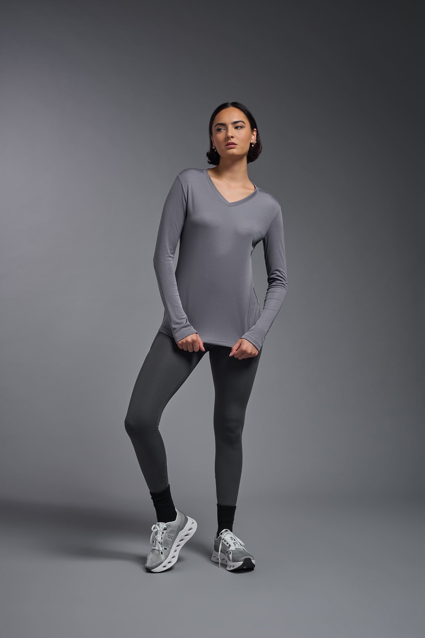 A female model wearing the women's DriMax V-Neck Long Sleeve Expert Tee  in the color steel gray, made out of 100% polyester, showing the relaxed fit from a front view. This shirt is quick-drying, moisture-wicking, with up to 30 UV protection and made in the USA. #steel