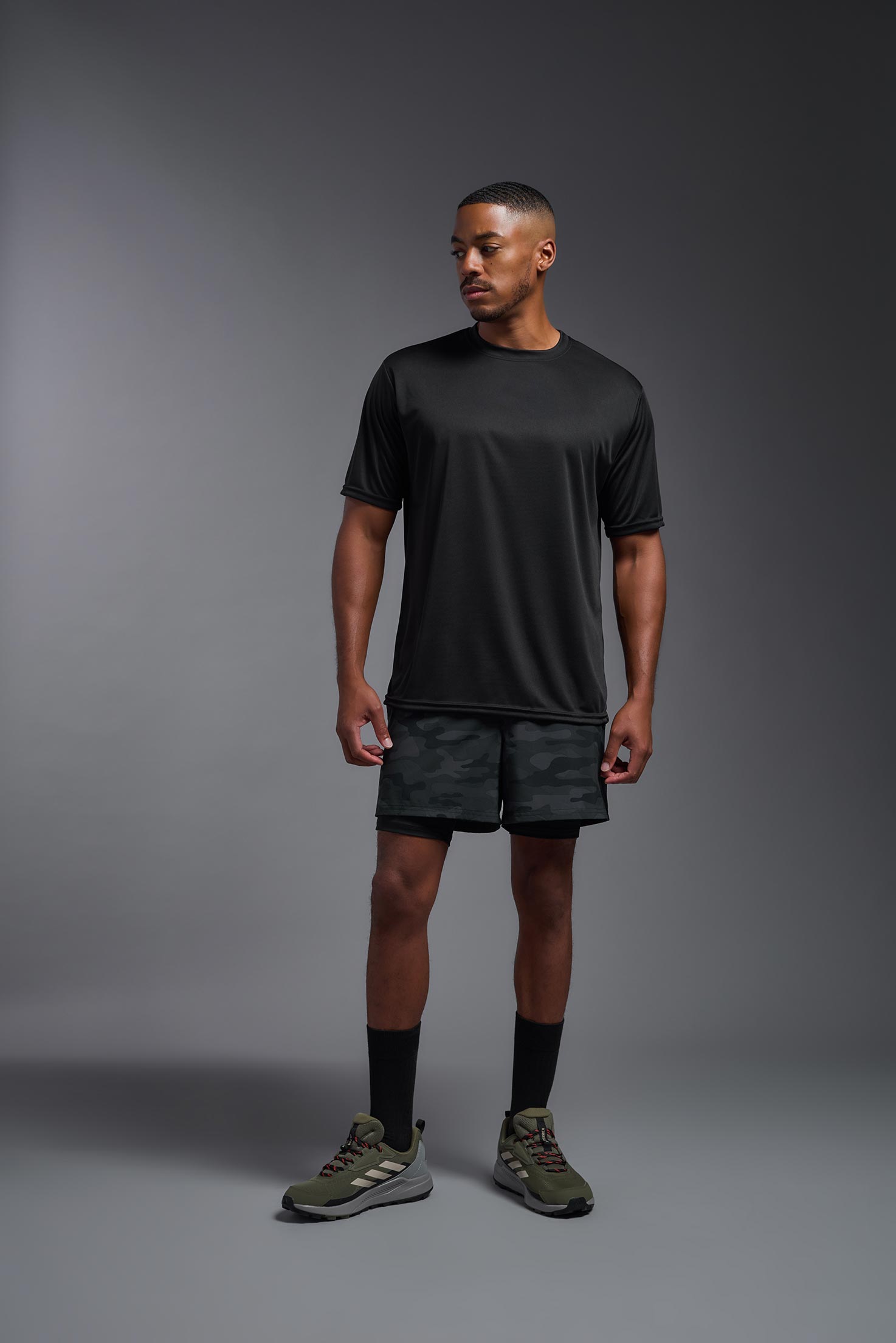 A male model wearing the men's DriMax Expert Tee in the color black, made out of 100% polyester, showing the relaxed fit from a front view. This shirt is moisture-wicking, quick-drying, and made in the USA. #black