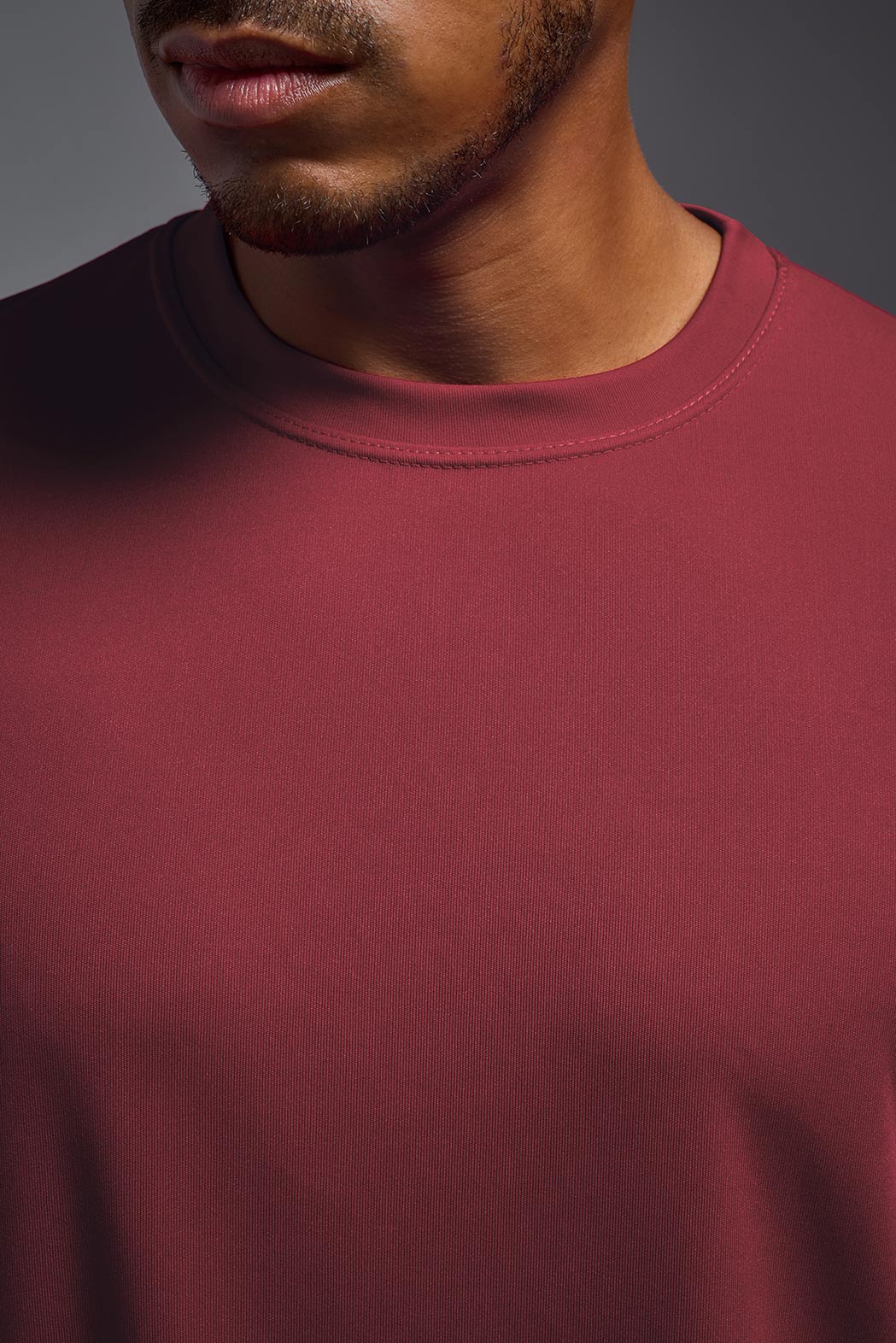 A male model wearing the men's DriMax Expert Tee in the color cardinal, made out of 100% polyester, showing the relaxed fit from a front close-up collar view. #cardinal