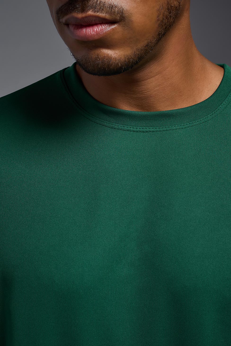 A male model wearing the men's DriMax Expert Tee in forest green, made out of 100% polyester, showing the relaxed fit from the collar. This shirt is moisture-wicking, quick-drying, and made in the USA. #forest-green