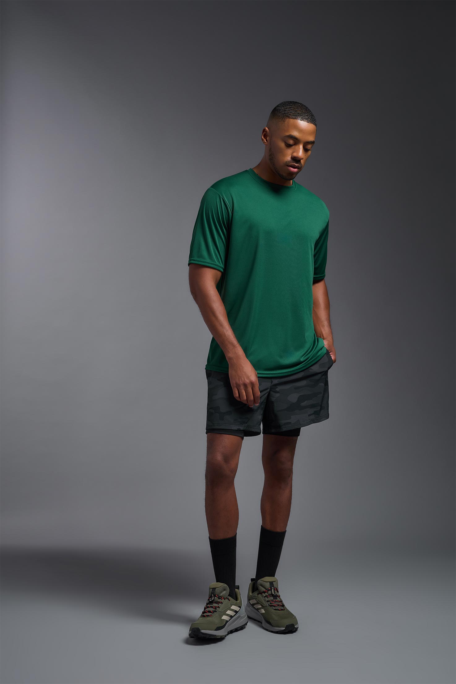 A male model wearing the men's DriMax Expert Tee in forest green, made out of 100% polyester, showing the relaxed fit from a front view. This shirt is moisture-wicking, quick-drying, and made in the USA. #forest-green