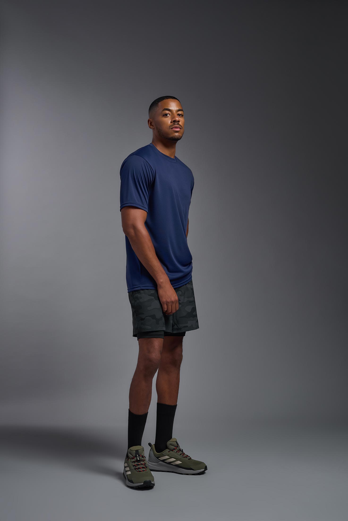 A male model wearing the men's DriMax Expert Tee in the color navy, made out of 100% polyester, showing the relaxed fit from a side view. #navy