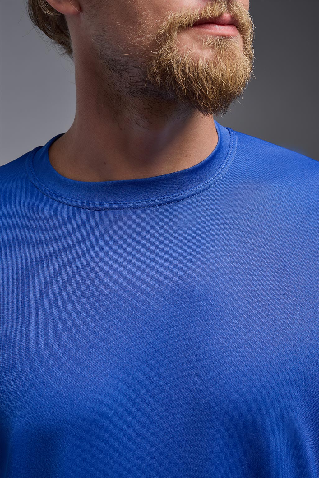 A male model wearing the men's DriMax Expert Tee in royal blue, made out of 100% polyester, showing the relaxed fit from a front collar detail view. #royal
