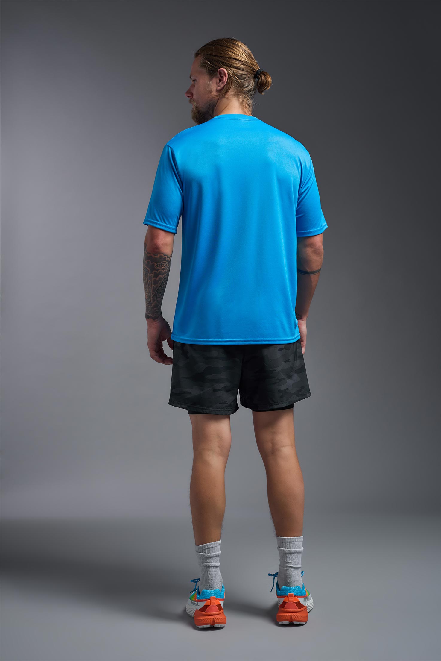 A male model wearing the men's DriMax Expert Tee in safety blue, made out of 100% polyester, showing the relaxed fit from a back view. #safety-blue