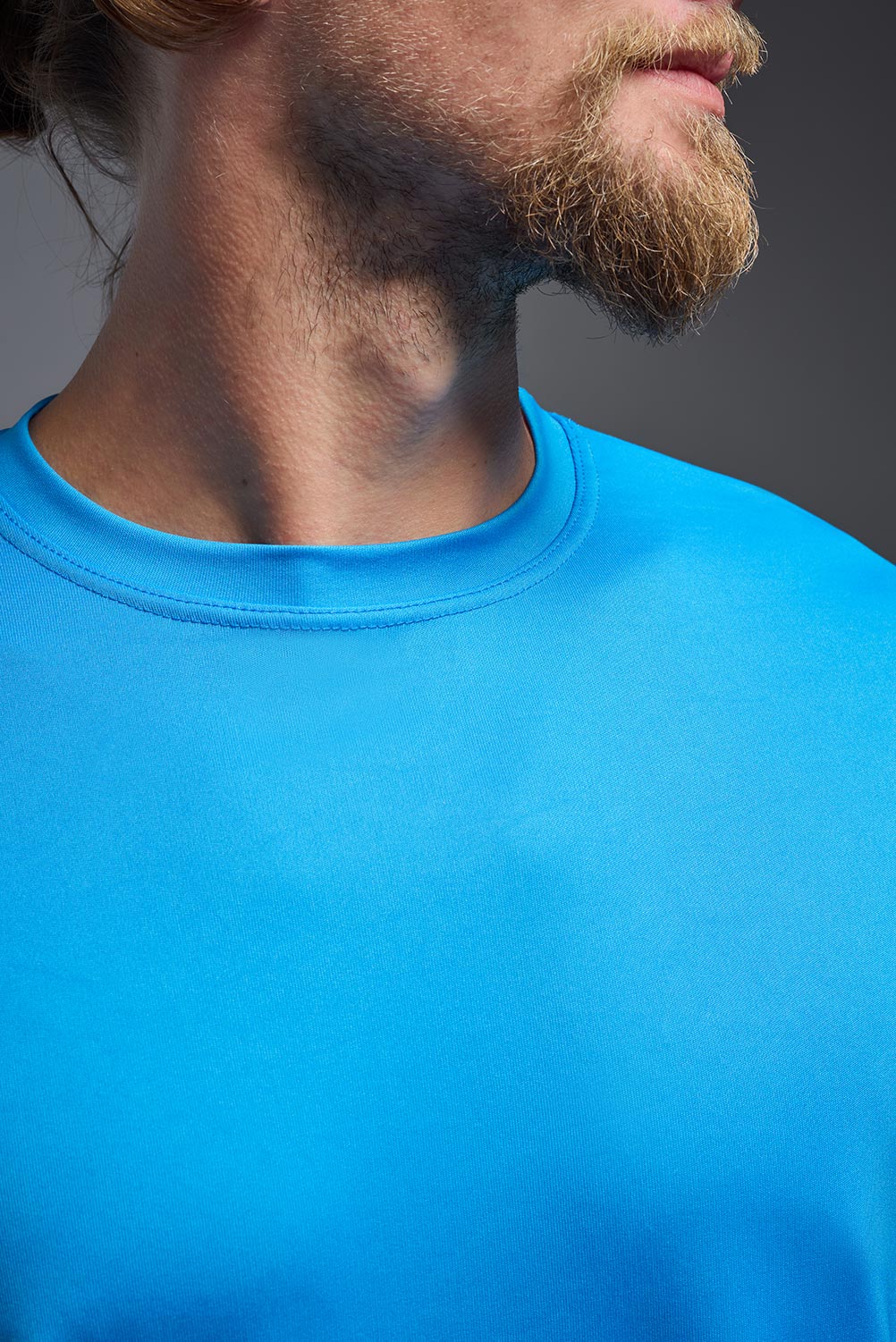 A male model wearing the men's DriMax Expert Tee in safety blue, made out of 100% polyester, showing the relaxed fit from a collar view. #safety-blue