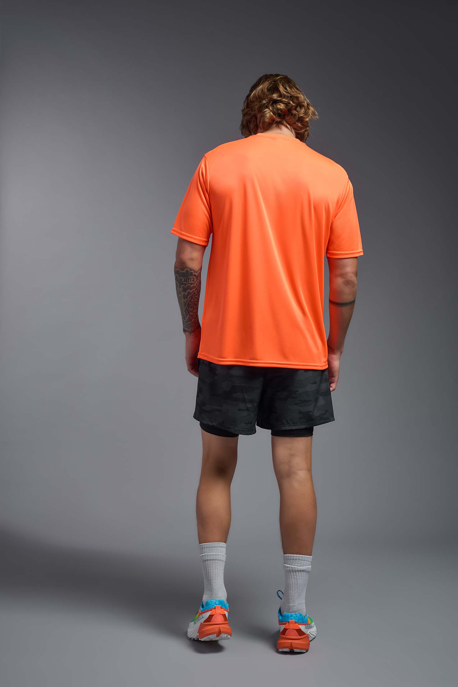 A male model wearing the men's DriMax Expert Tee in safety orange, made out of 100% polyester, showing the relaxed fit from a back view. #safety-orange