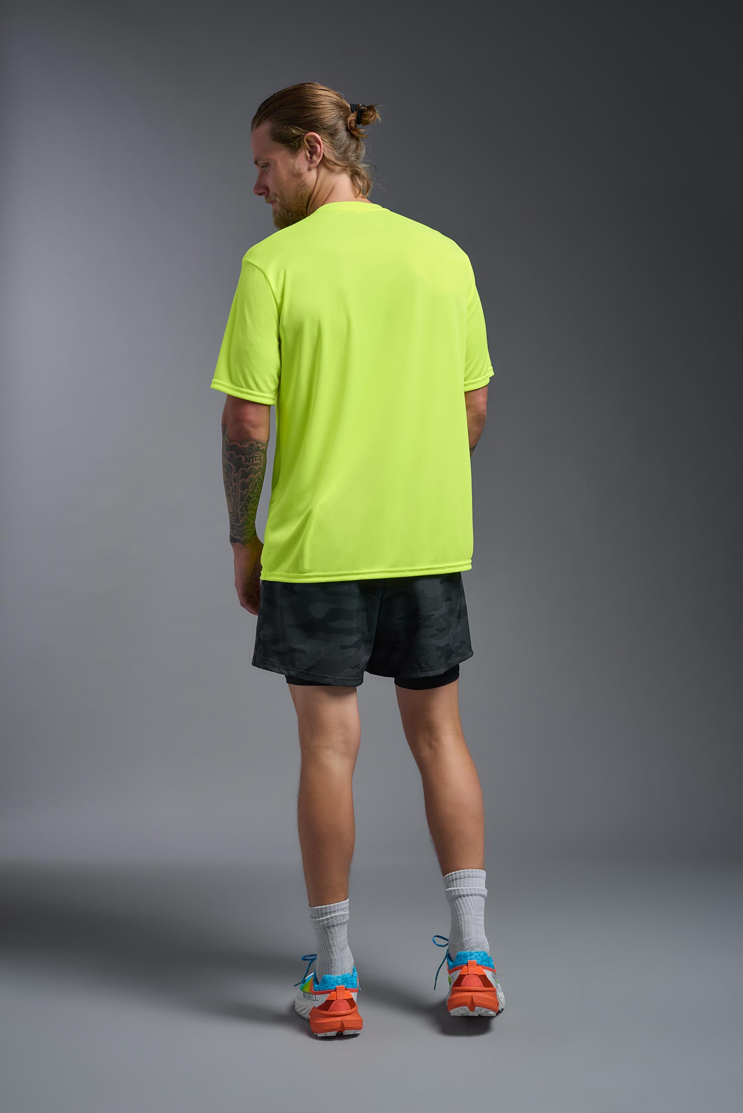 A male model wearing the men's DriMax Expert Tee in safety yellow, made out of 100% polyester, showing the relaxed fit from a back view. #safety-yellow
