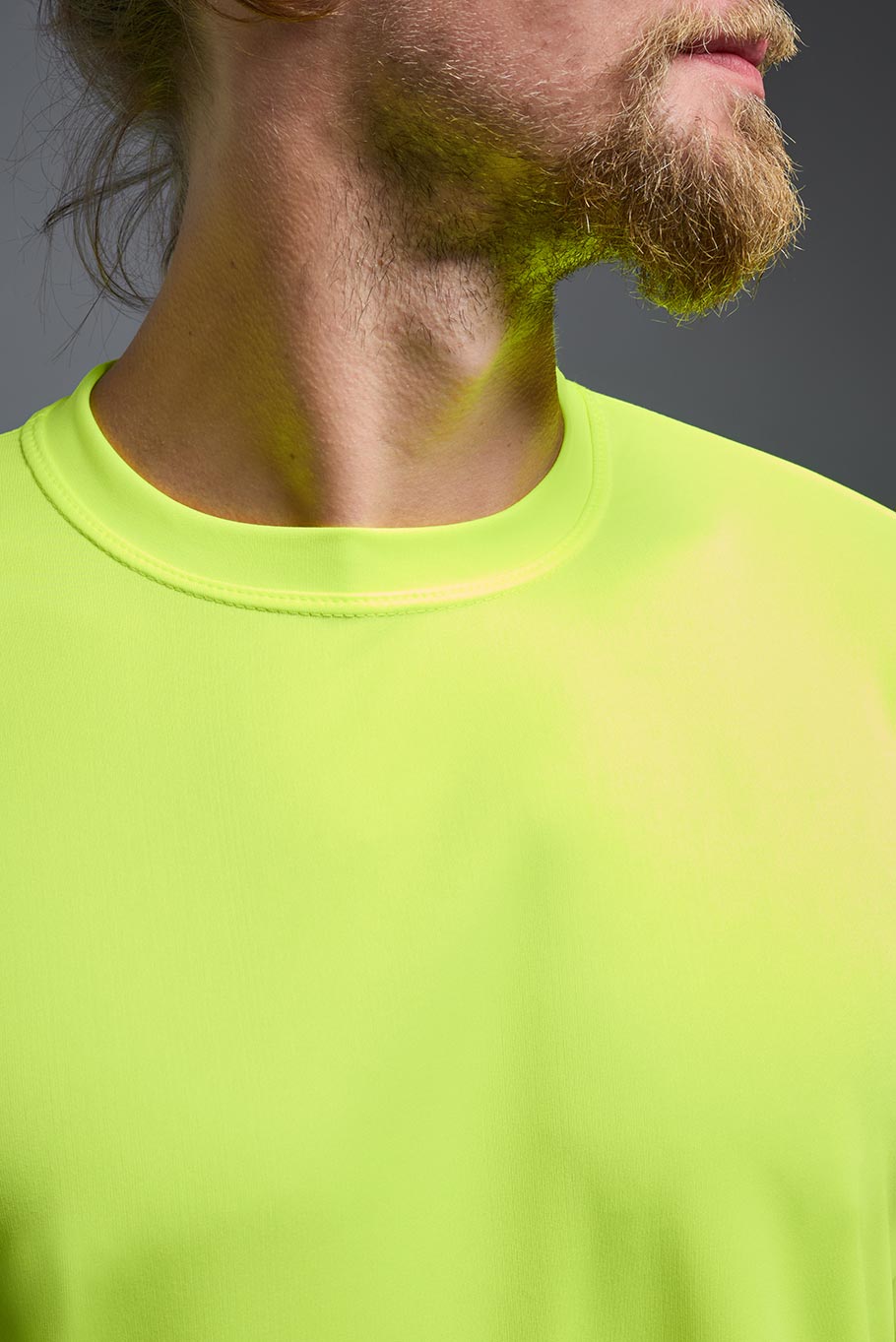 A male model wearing the men's DriMax Expert Tee in safety yellow, made out of 100% polyester, showing the relaxed fit collar detail. #safety-yellow