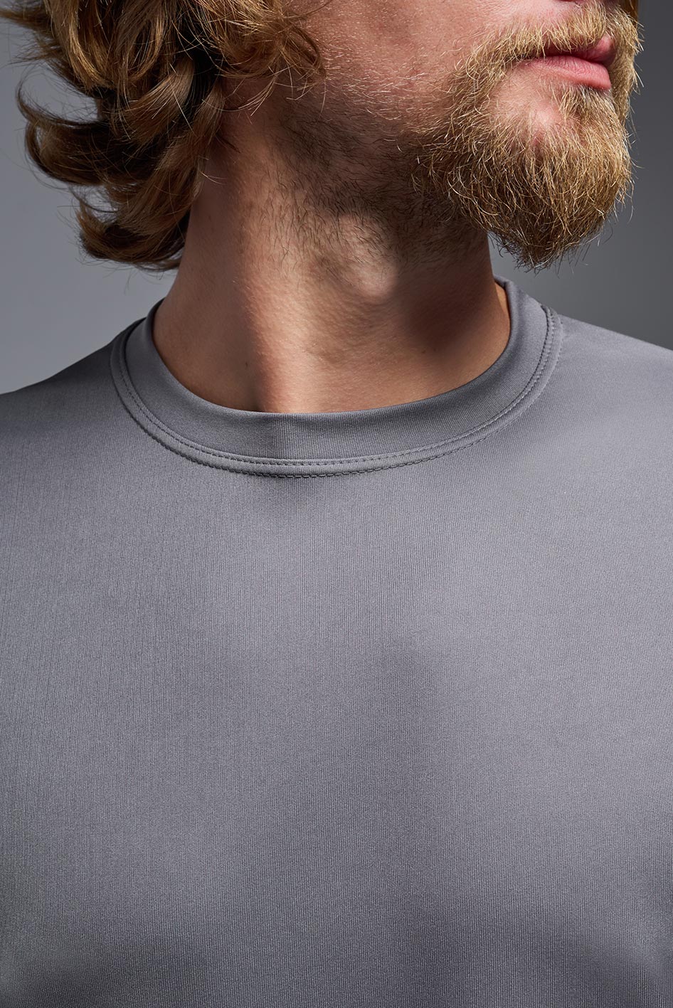 A male model wearing the men's DriMax Expert Tee in the color steel, made out of 100% polyester, showing the relaxed fit from a collar close-up view. This shirt is moisture-wicking, quick-drying, and made in the USA. #steel