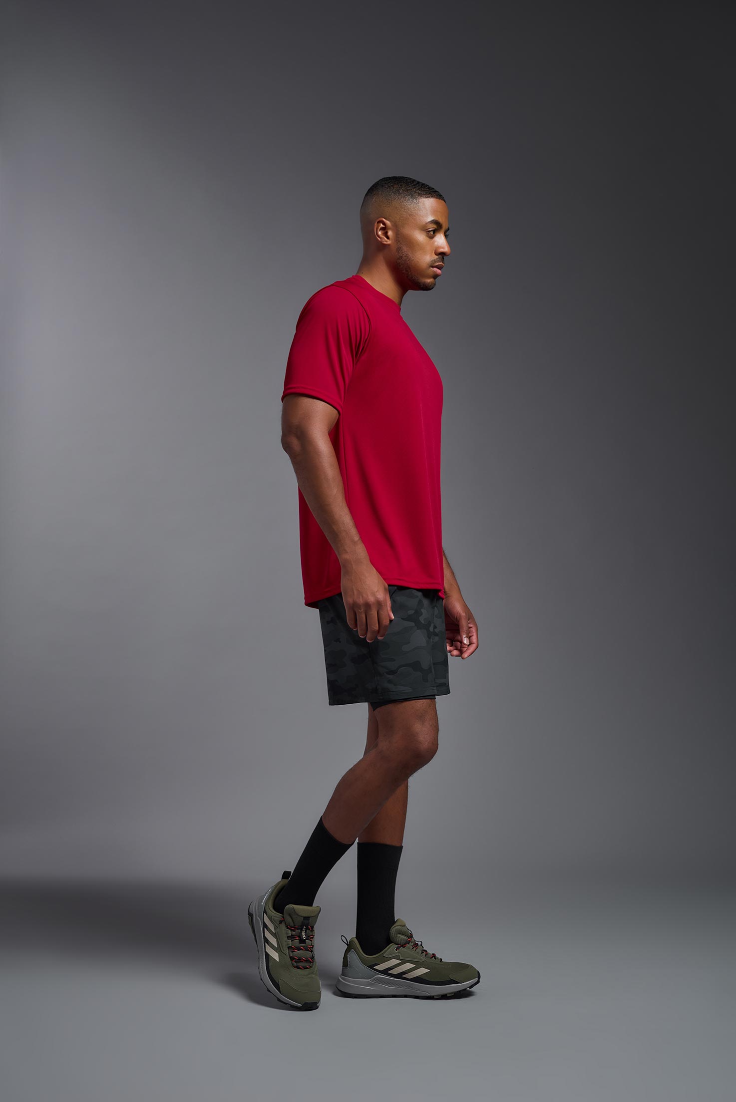 A male model wearing the men's DriMax Expert Tee in the color red, made out of 100% polyester, showing the relaxed fit from a side view. #red