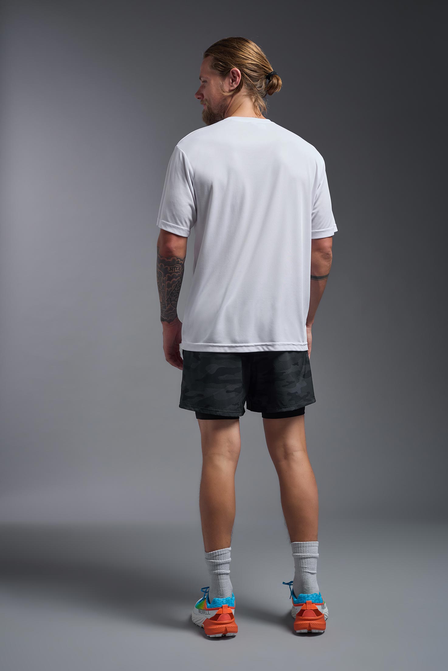 A male model wearing the men's DriMax Expert Tee in the color white, made out of 100% polyester, showing the relaxed fit from a back view. #white