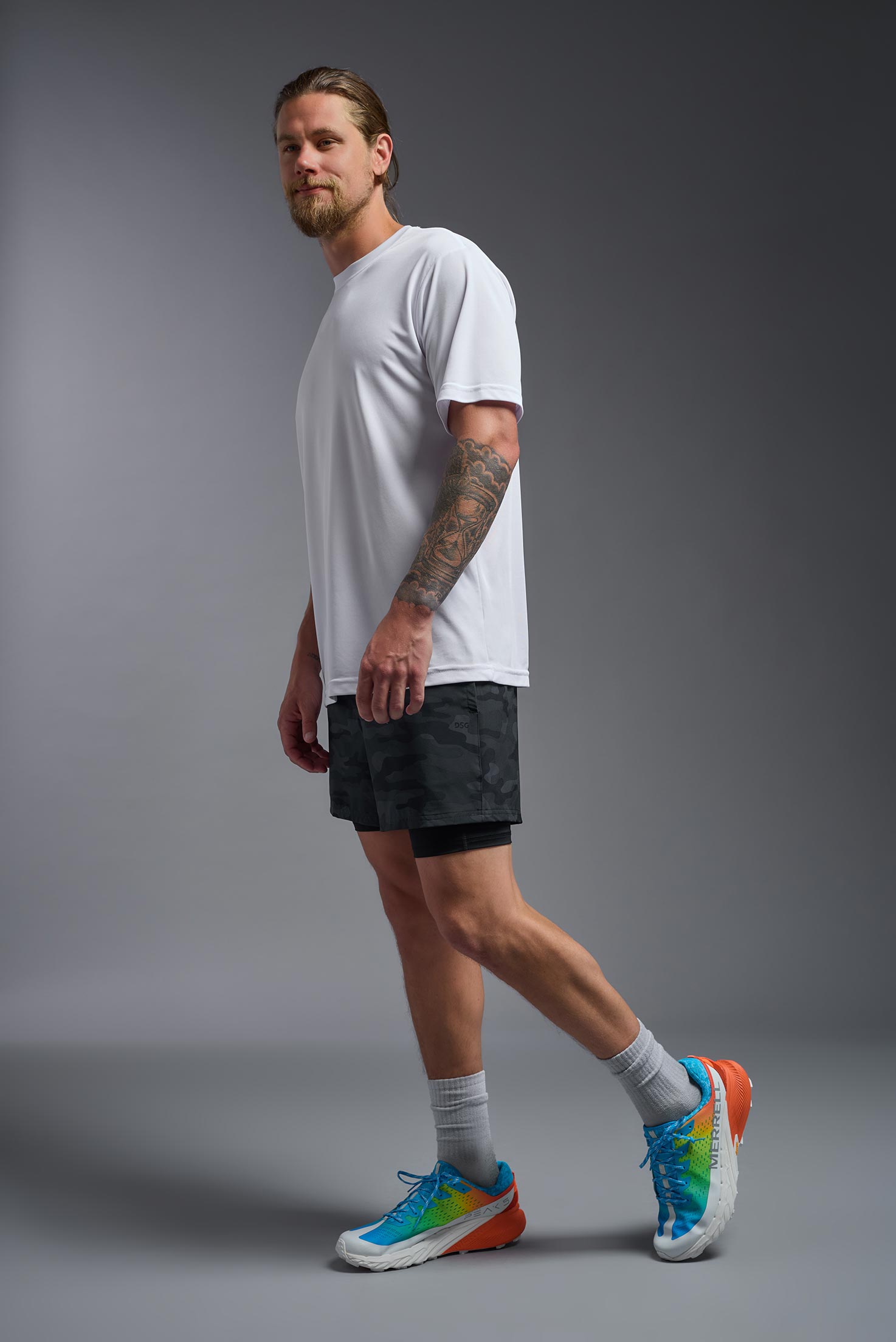 A male model wearing the men's DriMax Expert Tee in the color white, made out of 100% polyester, showing the relaxed fit from a side view. #white
