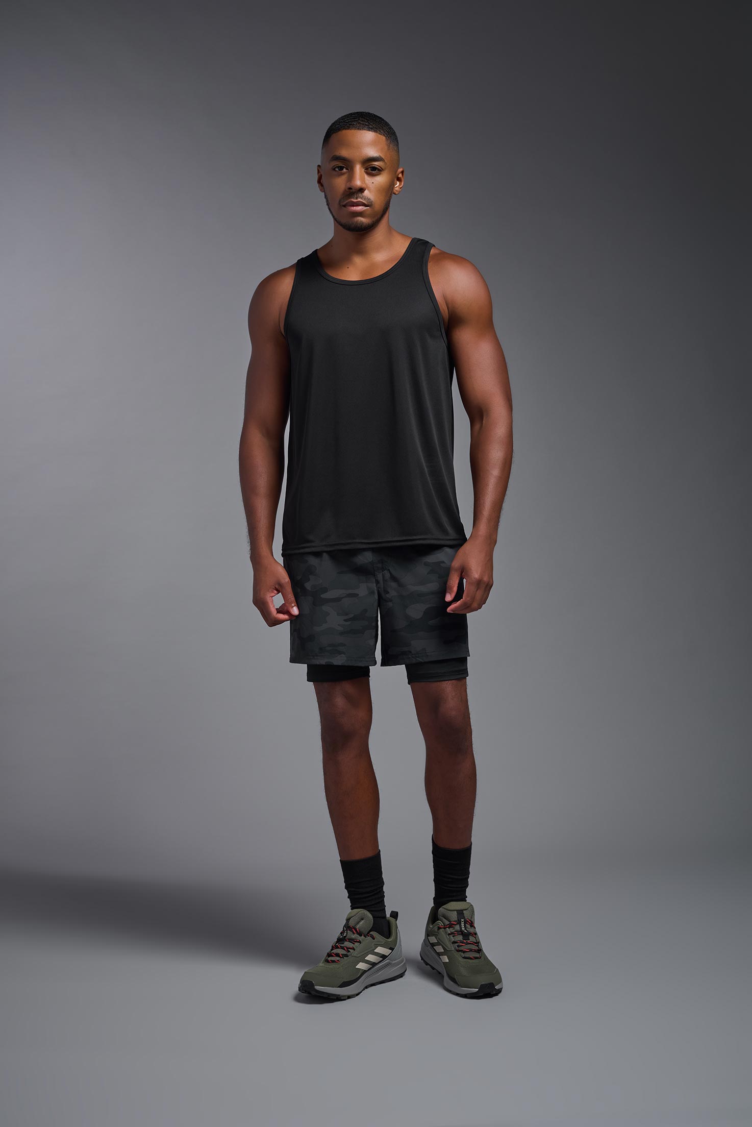 A male model wearing the men's DriMax Endurance Tank in the color black, made out of 100% polyester, showing the relaxed fit from a front view. #black