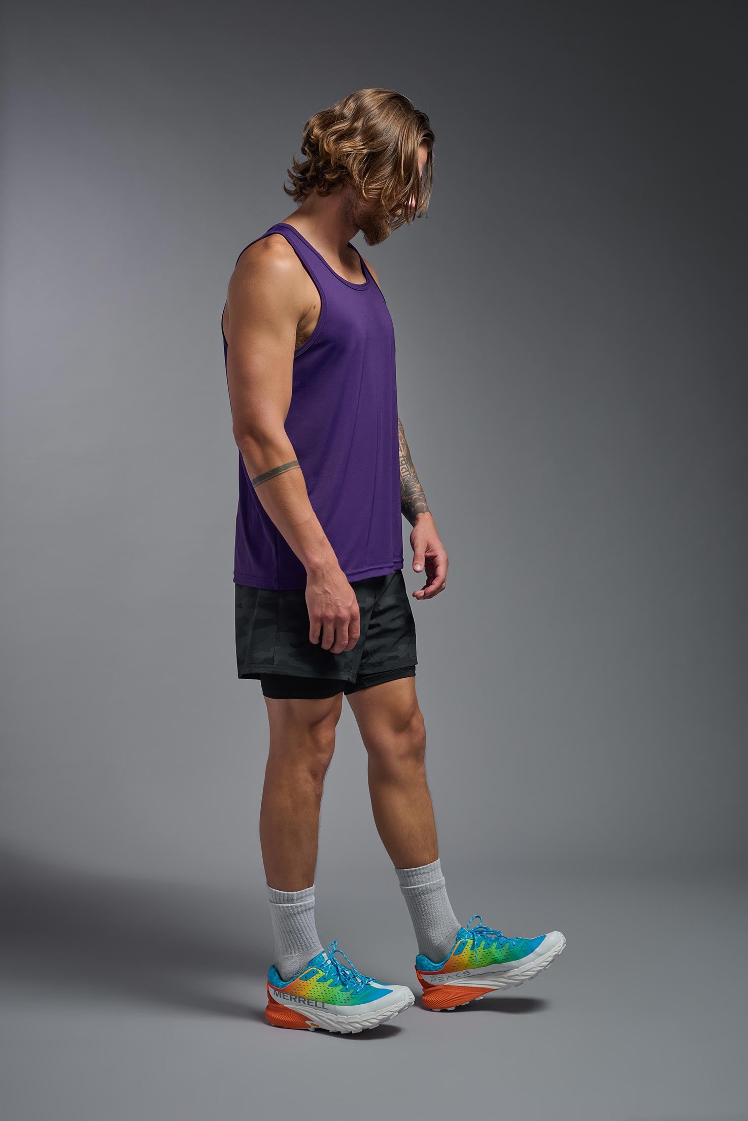 A male model wearing the men's DriMax Endurance Tank in the color deep purple, made out of 100% polyester, showing the relaxed fit from a side view. #deep-purple