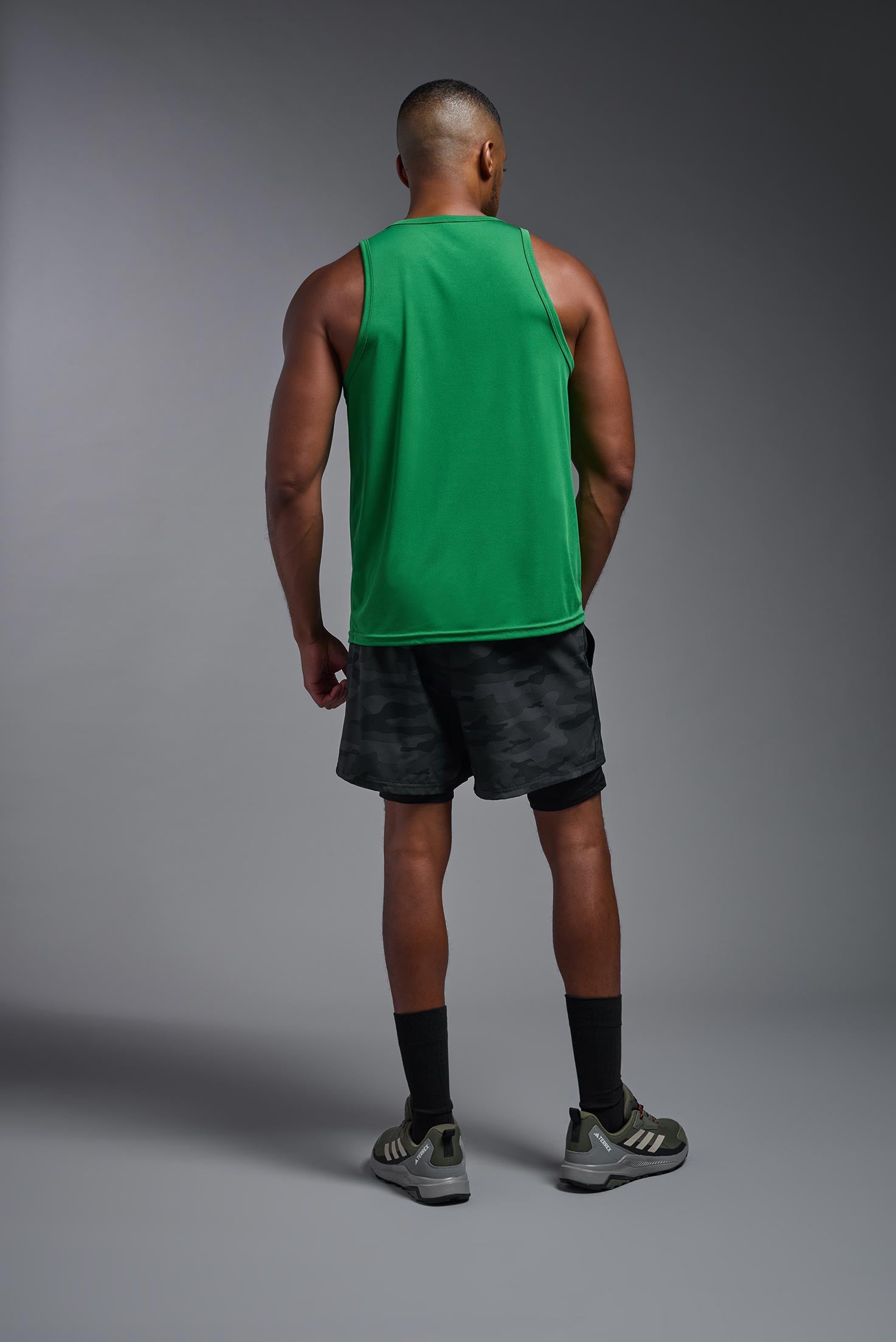 A male model wearing the men's DriMax Endurance Tank in the color kelly green, made out of 100% polyester, showing the relaxed fit from a back view. #kelly