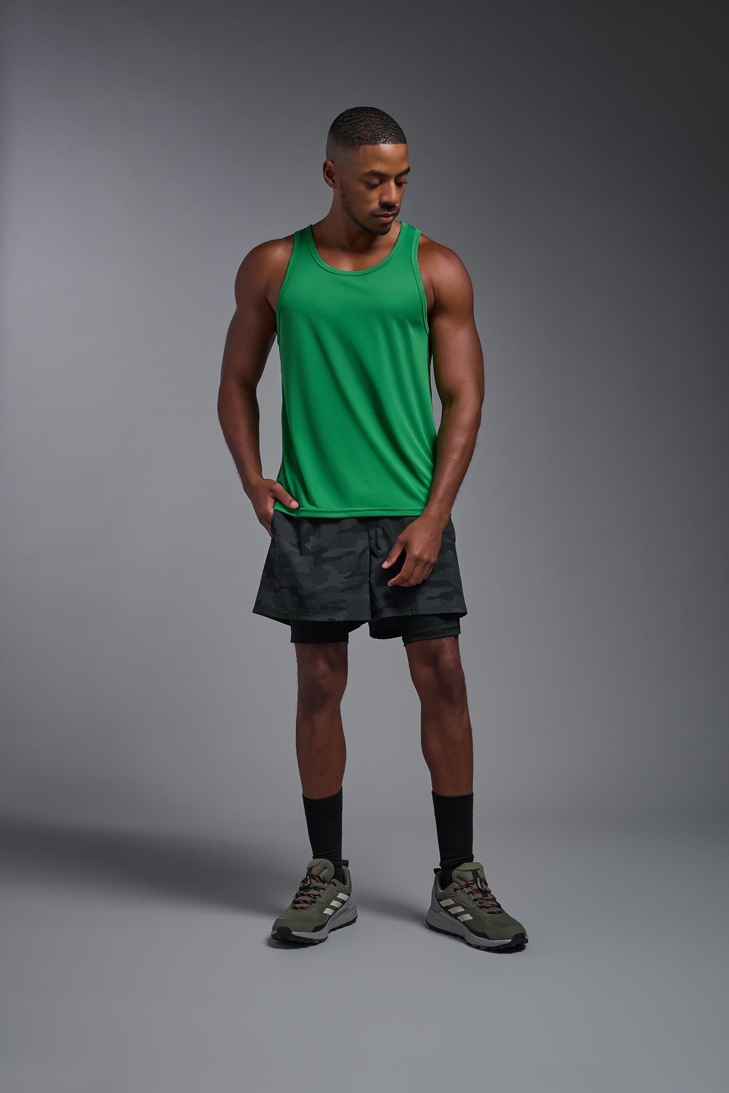 A male model wearing the men's DriMax Endurance Tank in the color kelly green, made out of 100% polyester, showing the relaxed fit from a front view. #kelly