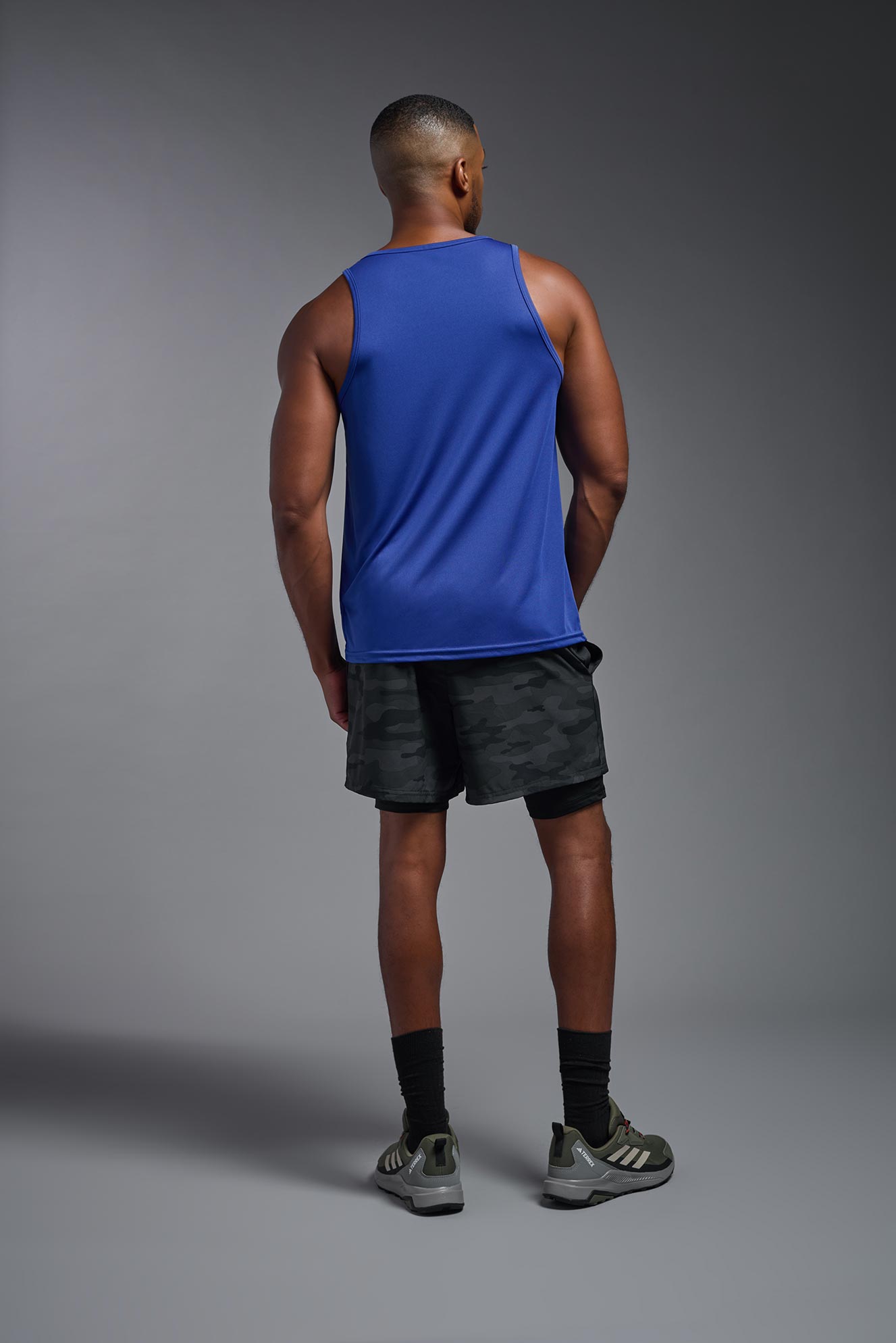 A male model wearing the men's DriMax Endurance Tank in the color royal blue, made out of 100% polyester, showing the relaxed fit from a back view. #royal